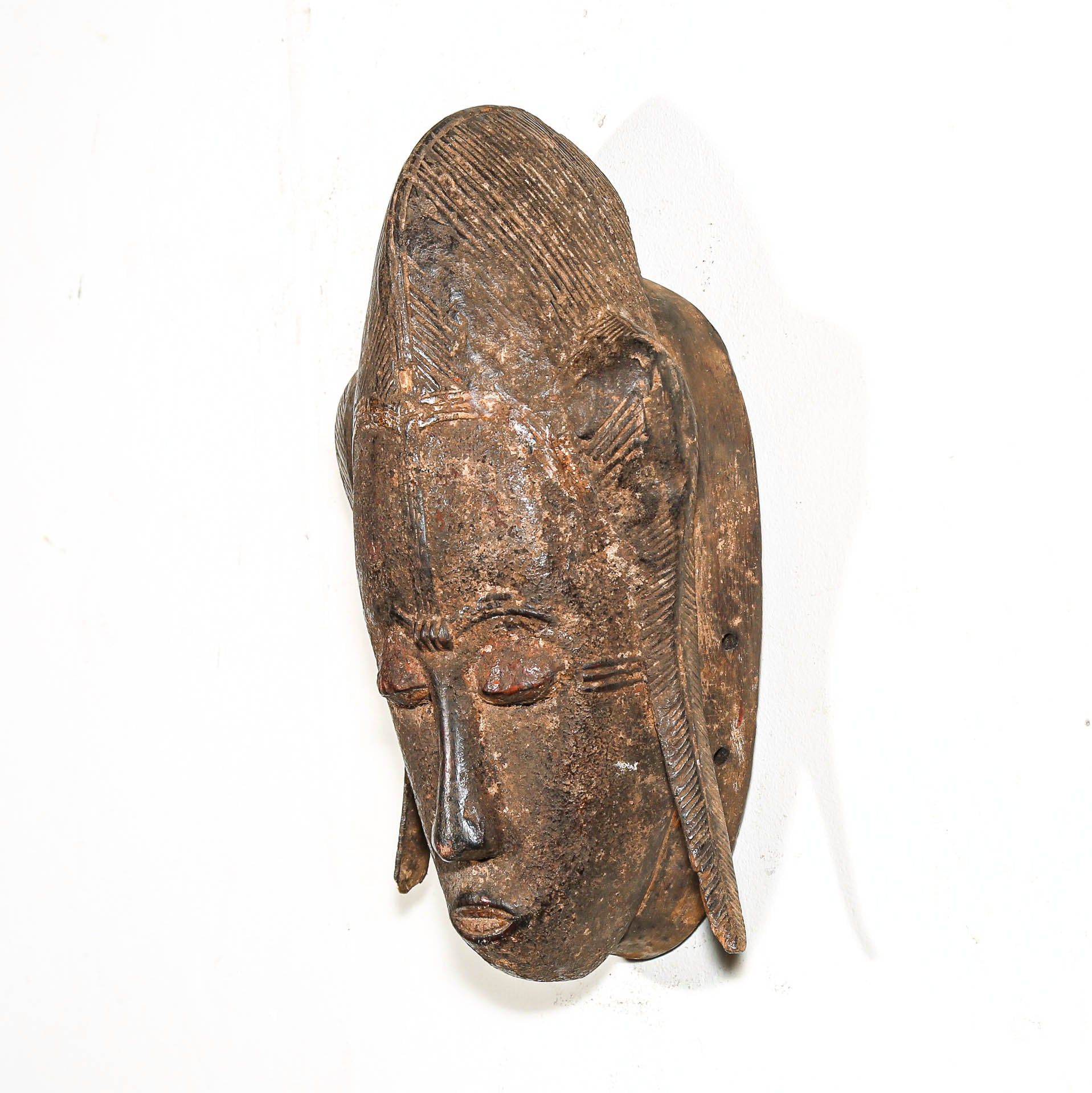 Bronze mask with detailed features on a white background