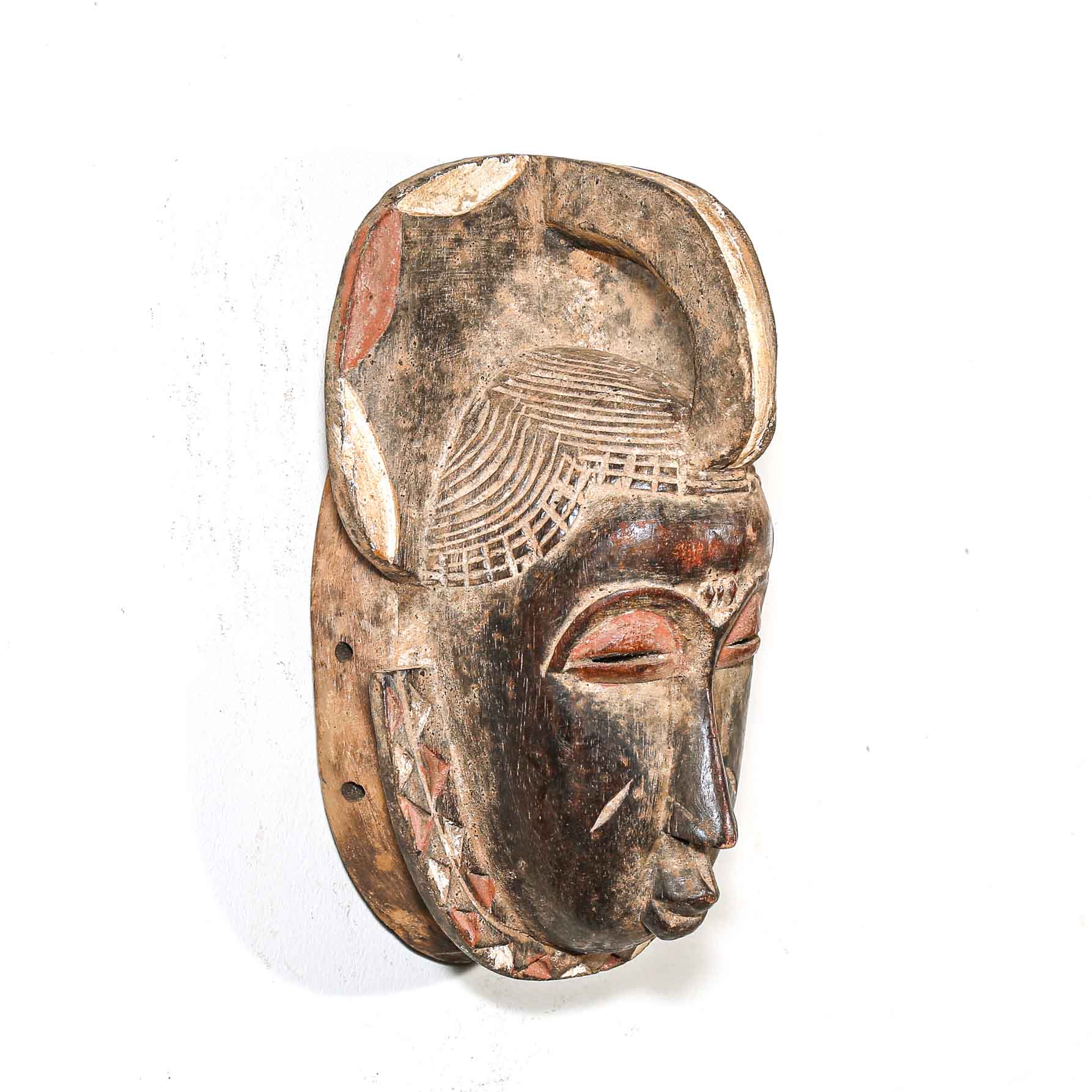 Traditional wooden mask with intricate carvings on a white background