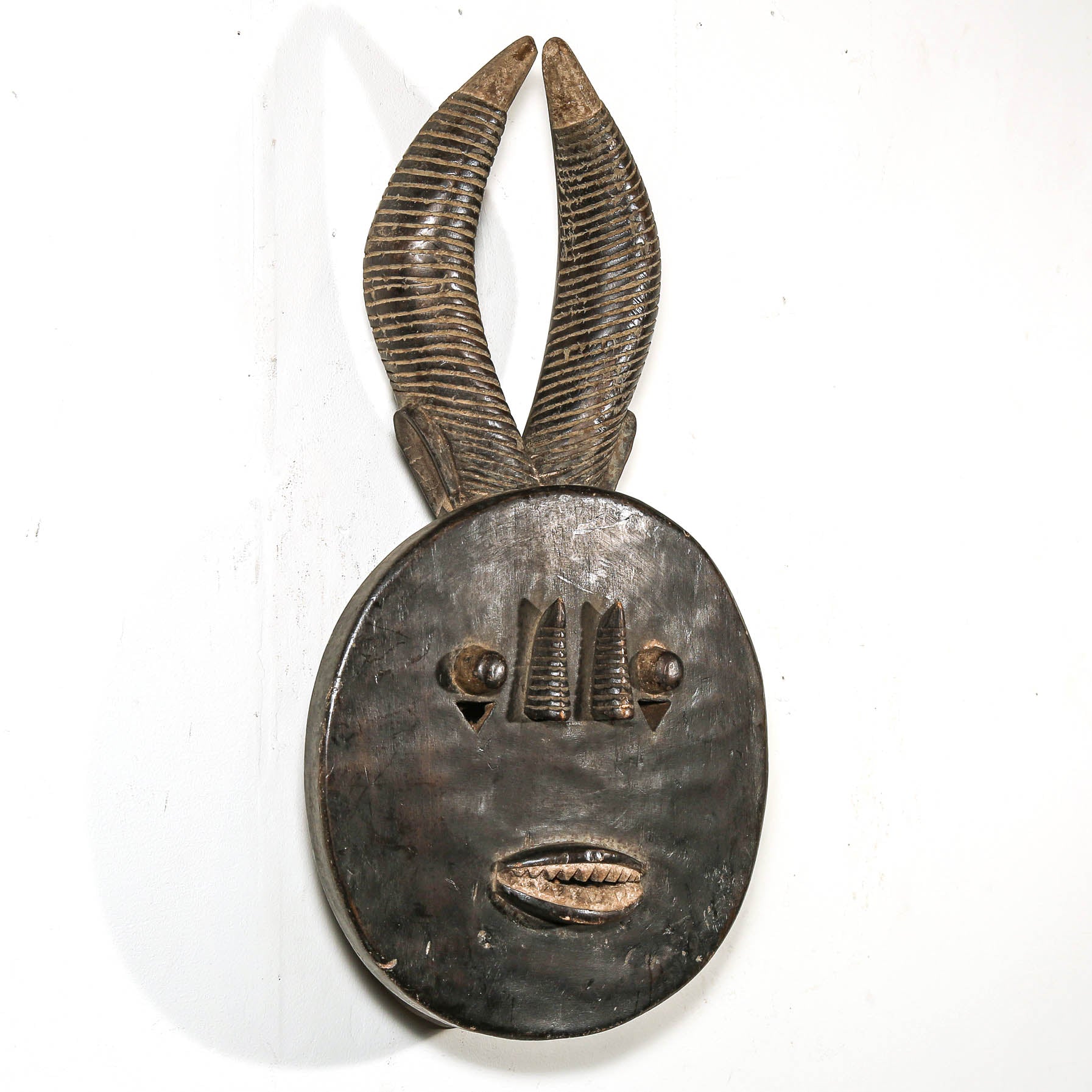 Decorative black african mask with antelope horns on a white background