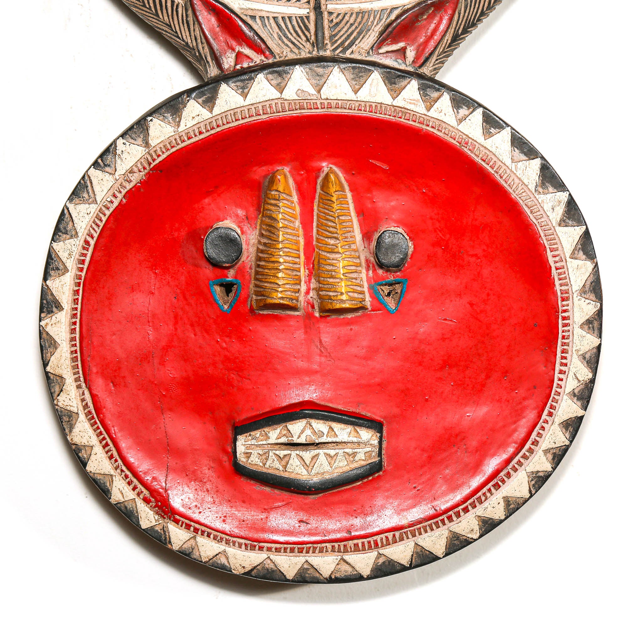 Decorative tribal mask with red face, gold accents, and geometric patterns on a white background