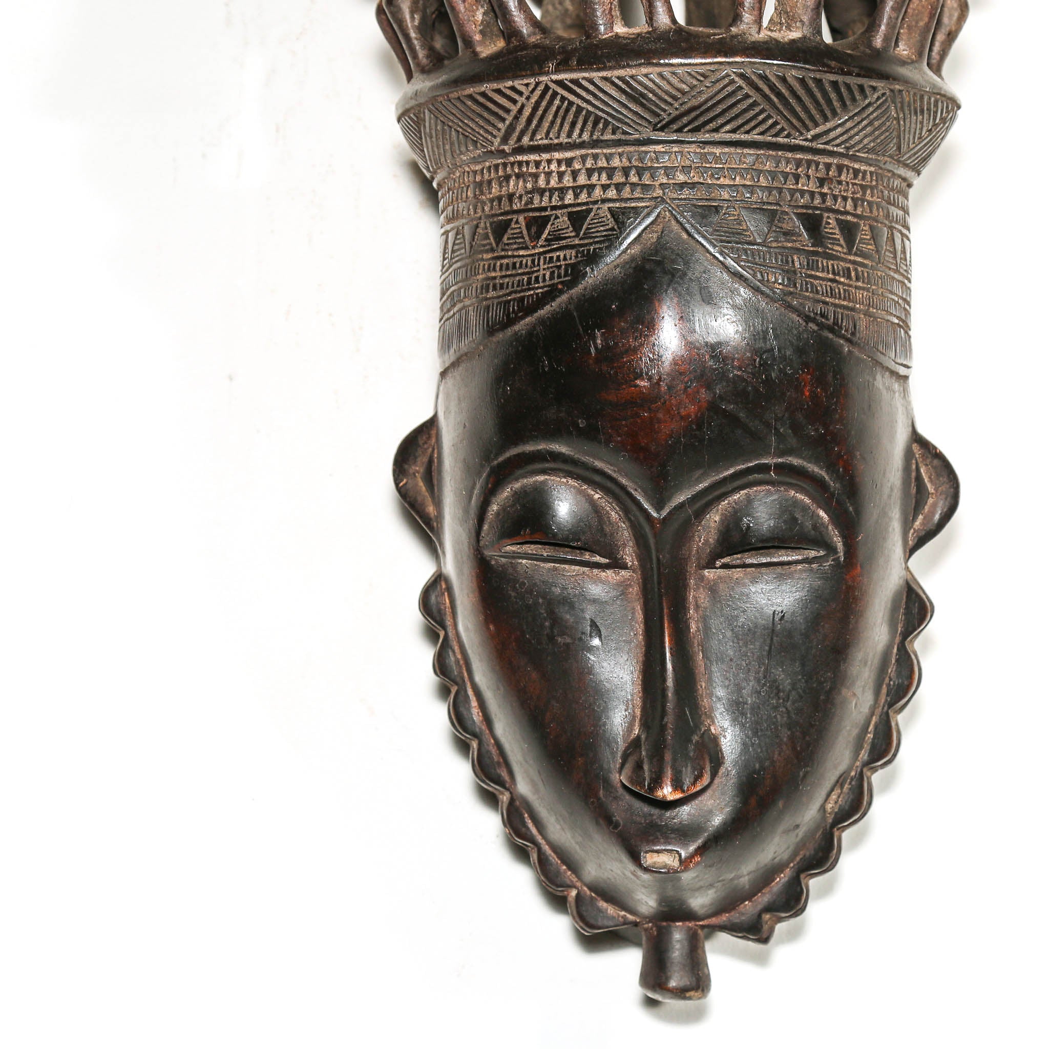 African mask with intricate carvings on a white background