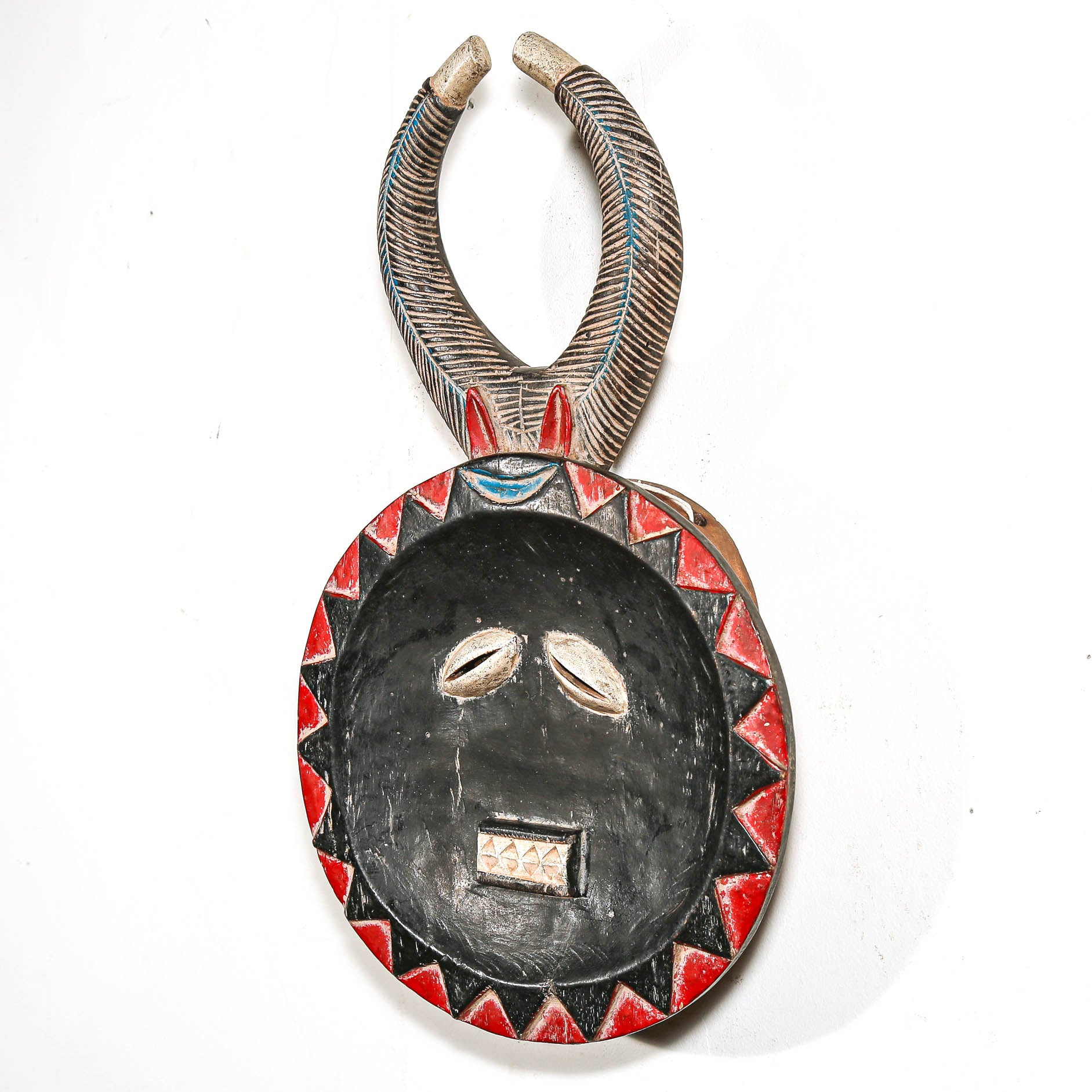 Decorative ceremonial tribal African art mask with red and black face patterns on a white background