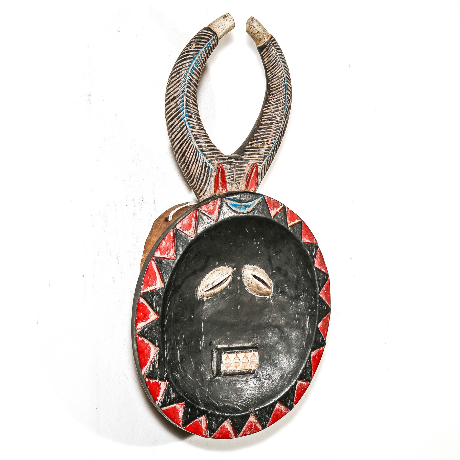 Decorative ceremonial tribal African art mask with red and black face patterns on a white background