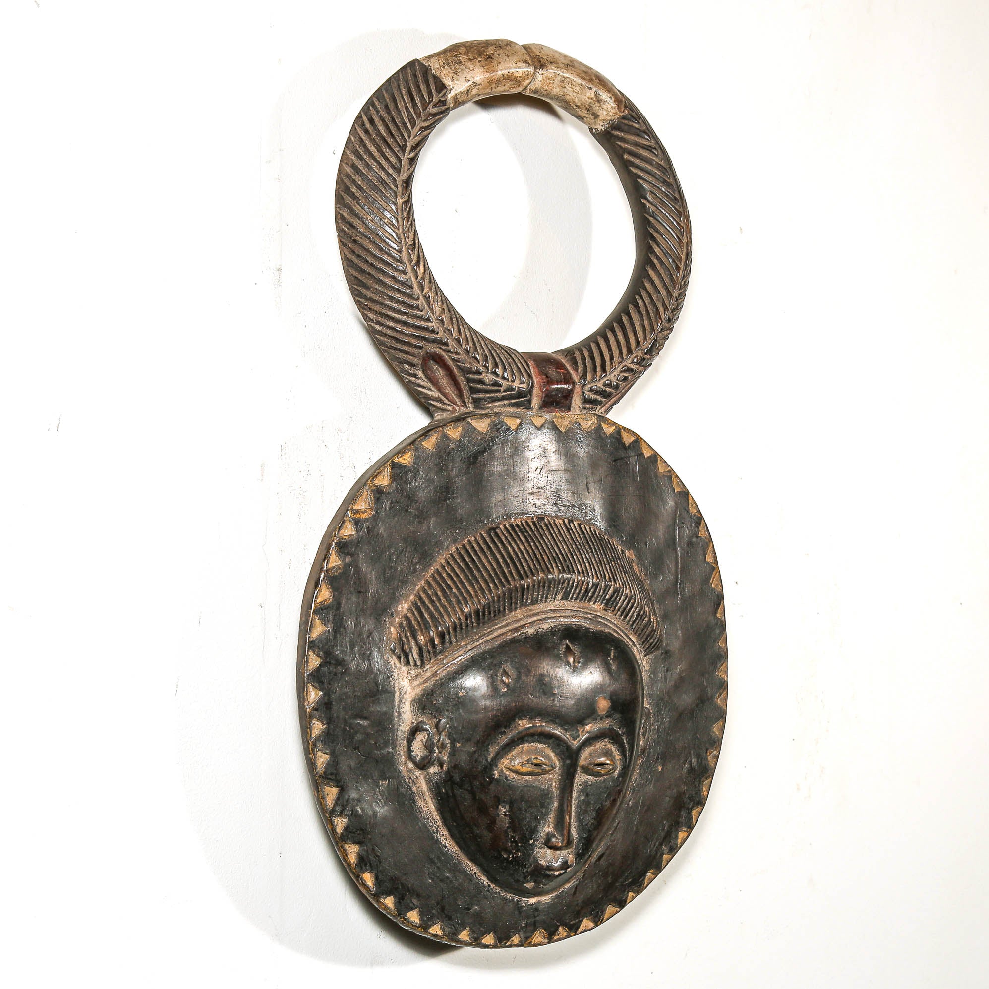 Decorative black African art mask with face design on a white background