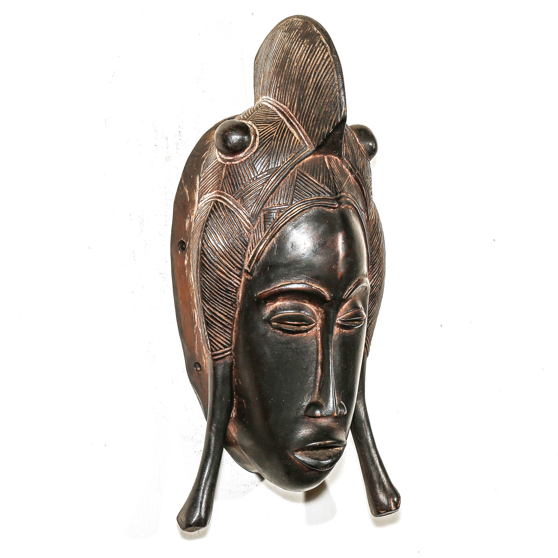 black wood mask with detailed facial features and headdress on a white background