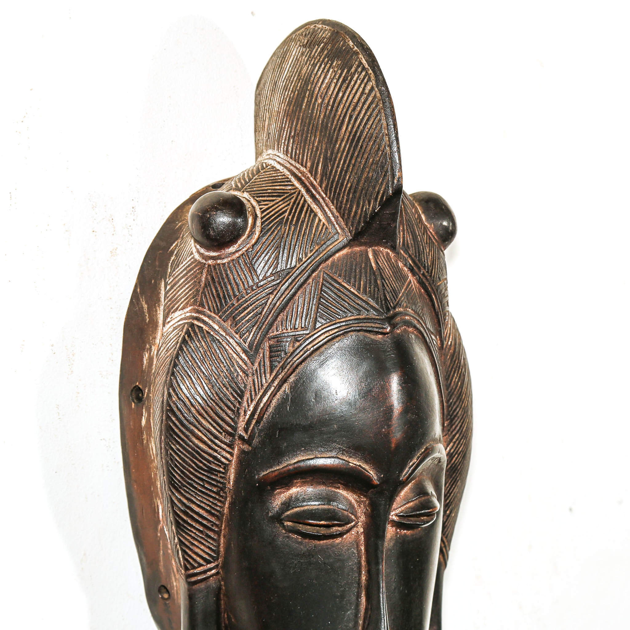 black wood art mask with detailed patterns and beads on a white background