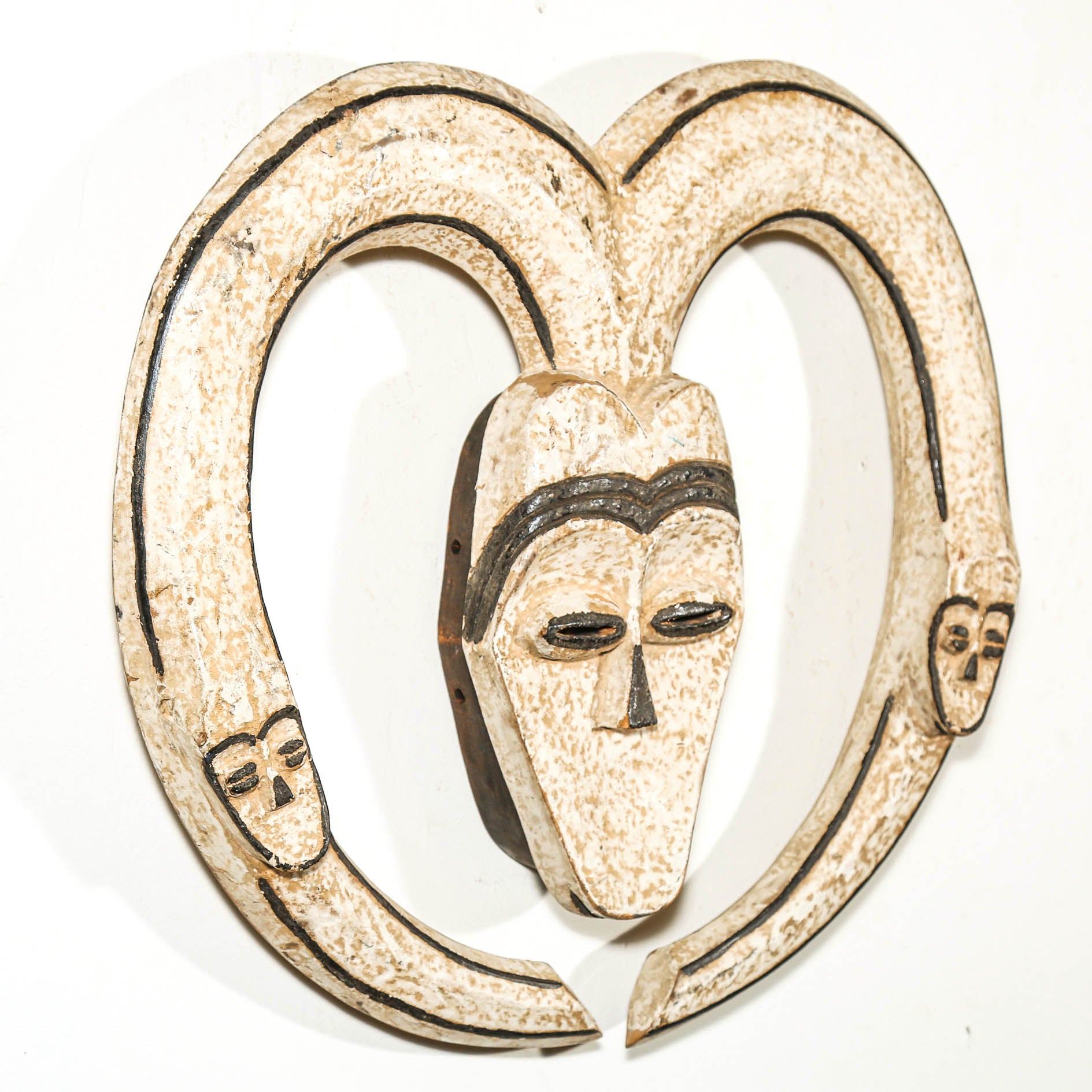 Decorative wall hanging African mask with a heart shape and black lines on a white background