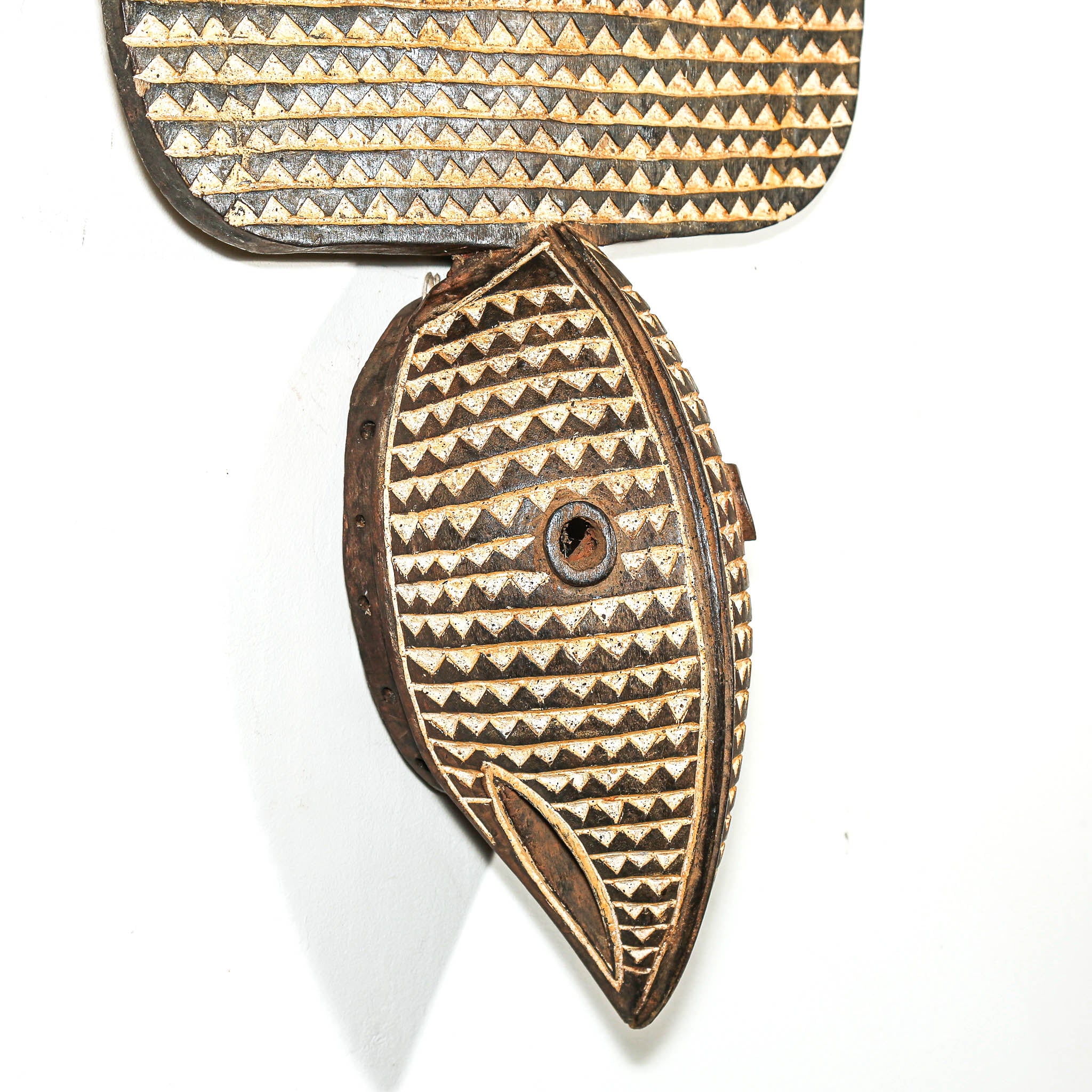 Decorative wooden fish-shaped object with pyramid patterns on a white background