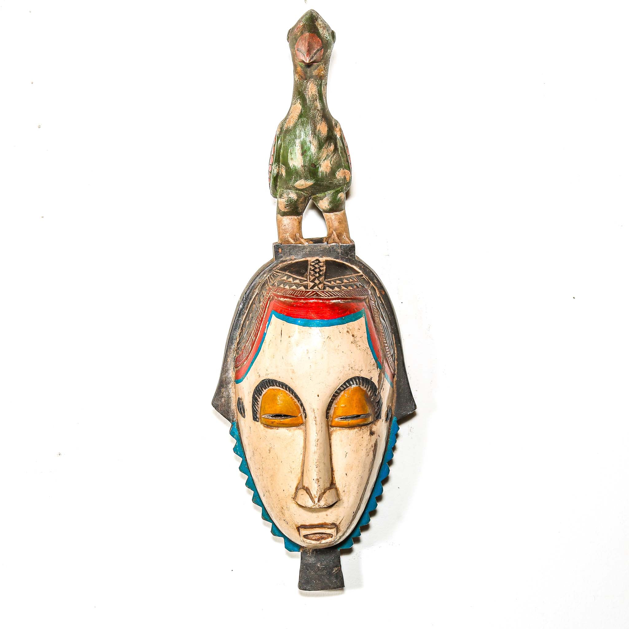 Decorative ceremonial African mask with a bird on top against a white background