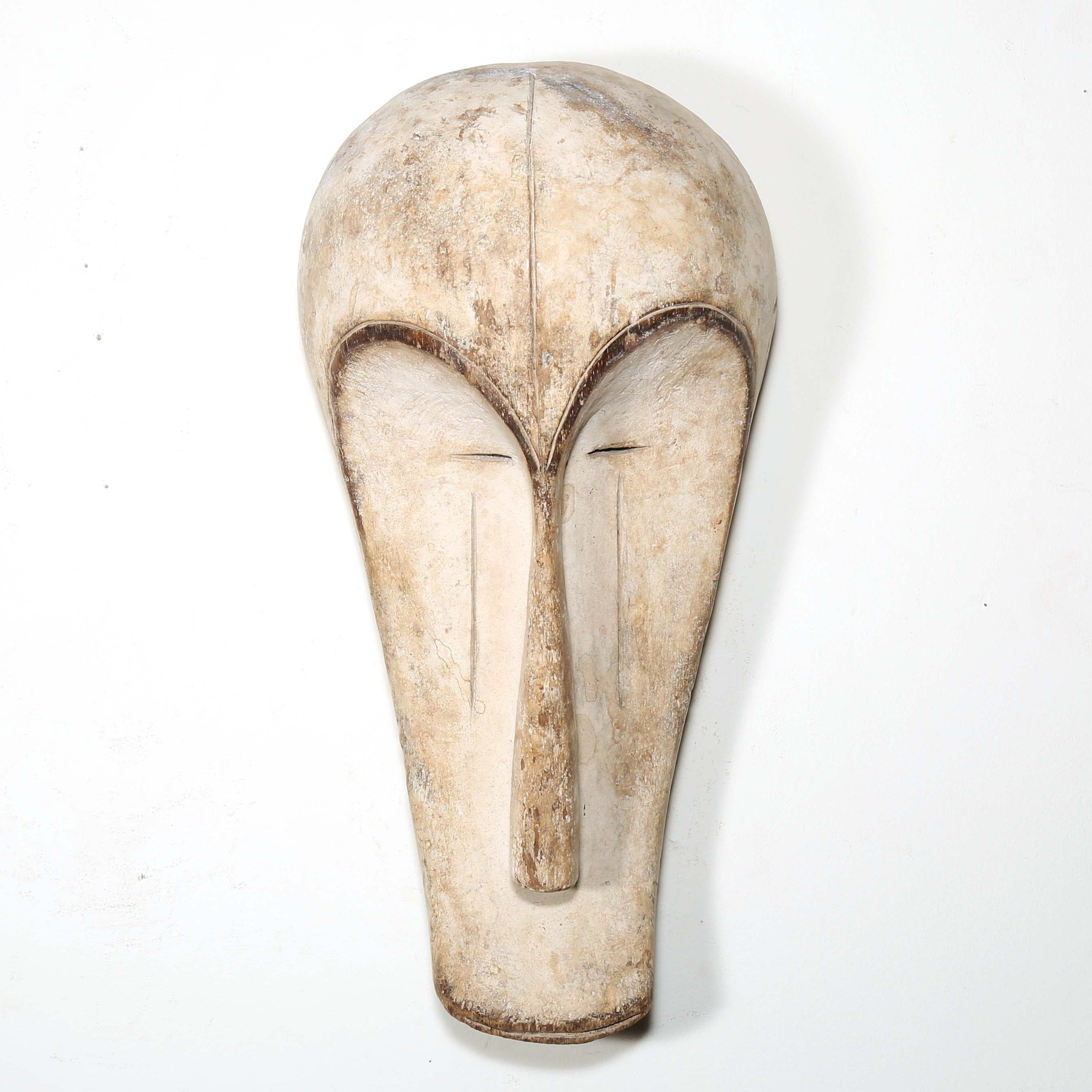 Authentic African mask to purchase online with neutral color designs hanging on a white wall