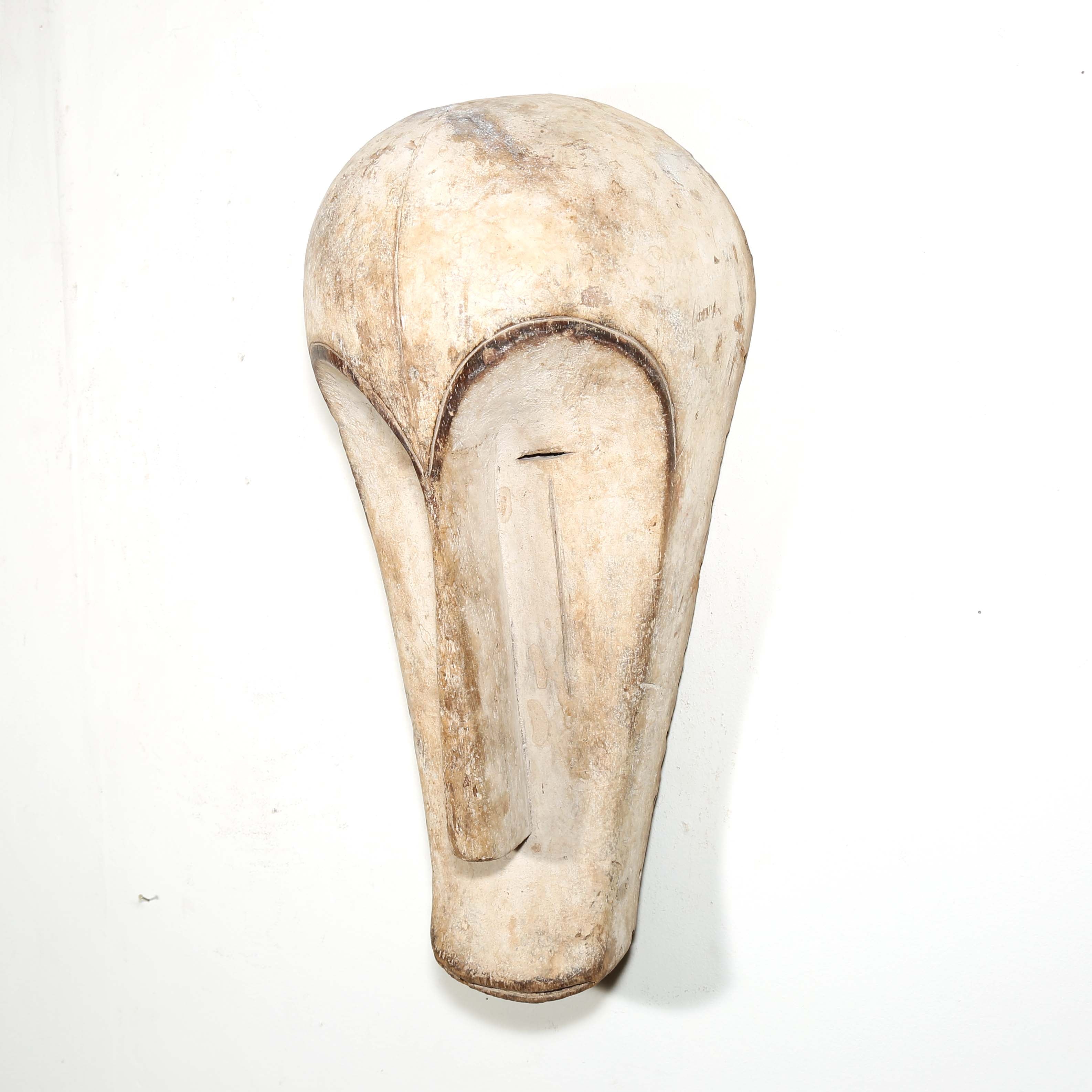 Authentic African mask to purchase online with neutral color designs hanging on a white wall