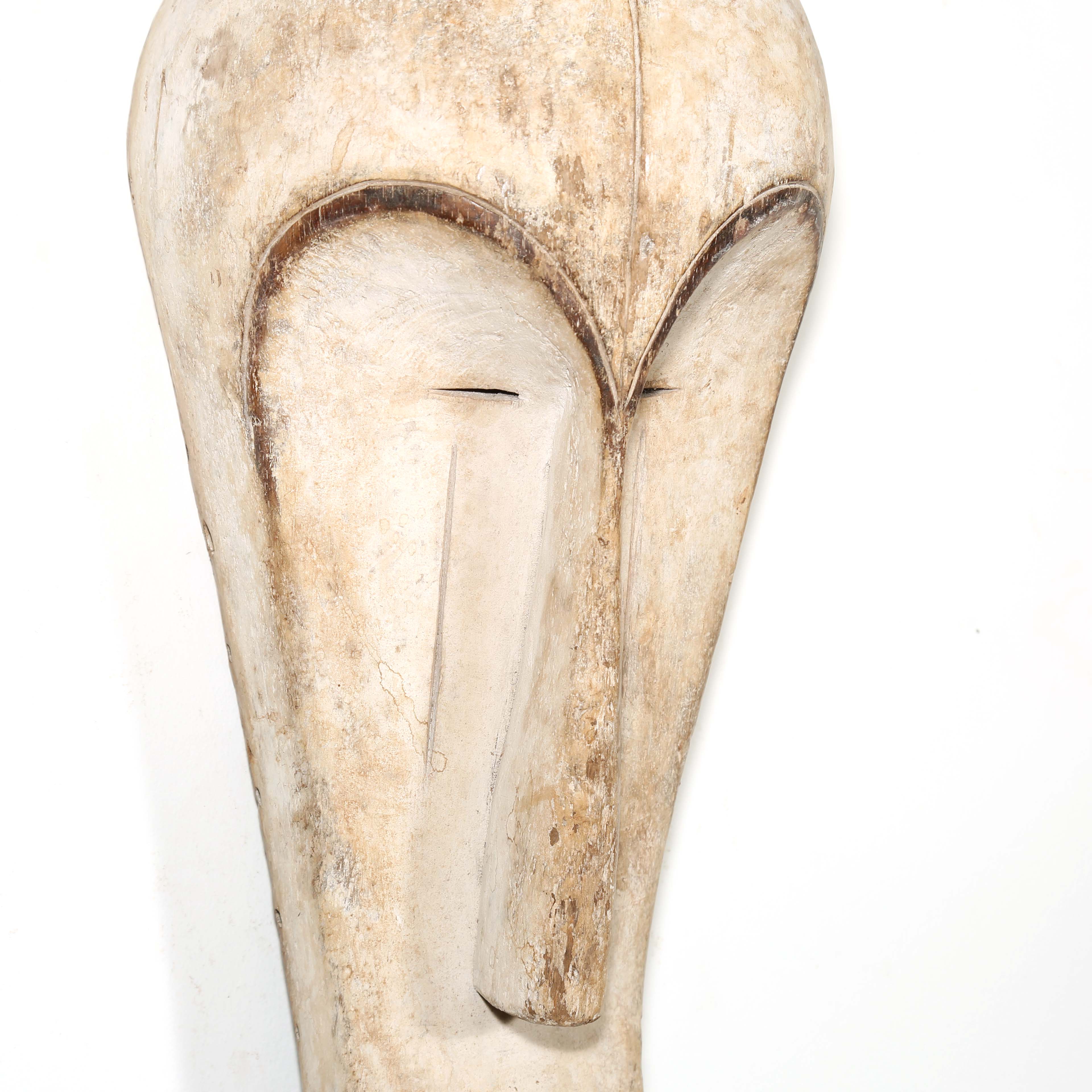 Authentic African mask to purchase online with neutral color designs hanging on a white wall