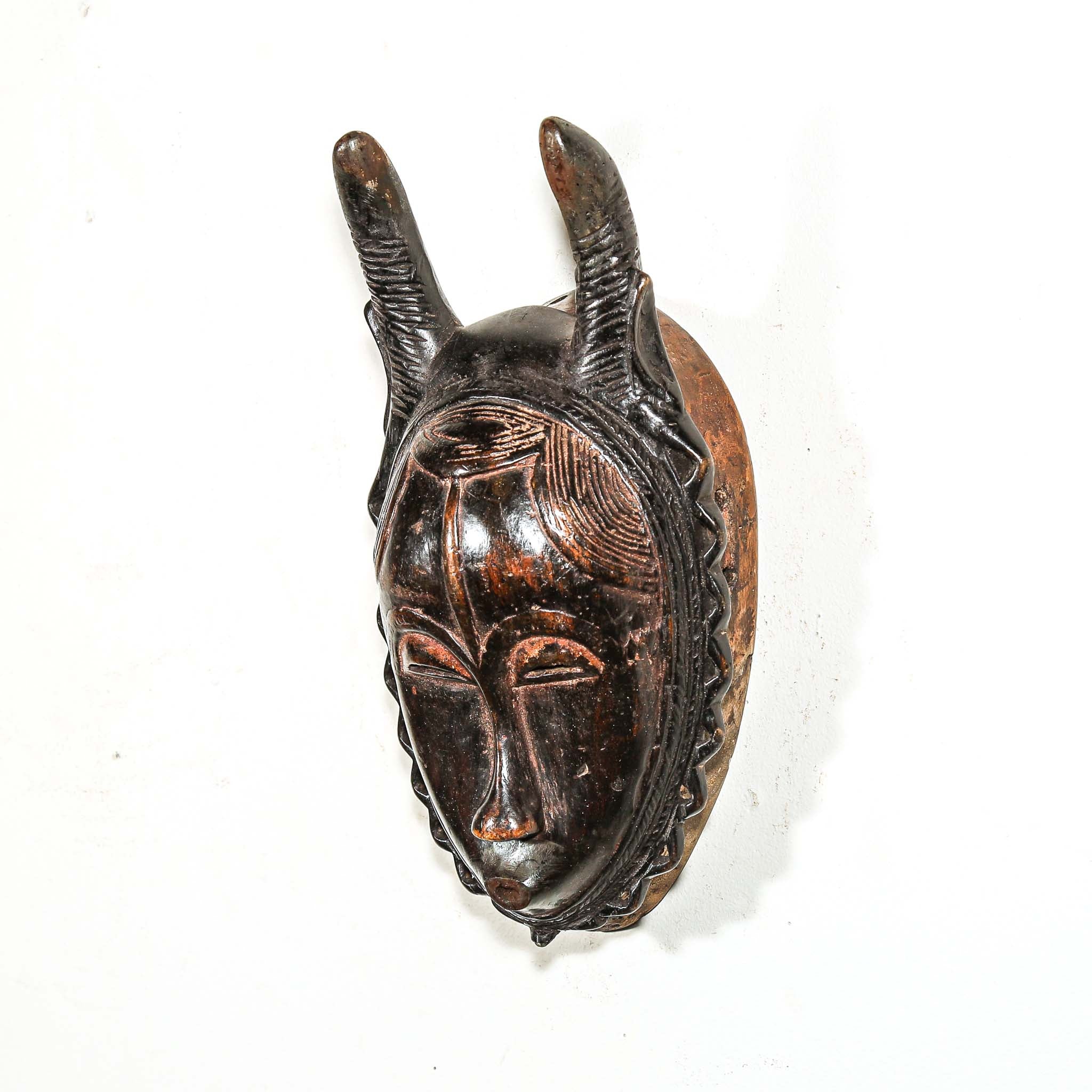 brown and black African mask with horns on a white background