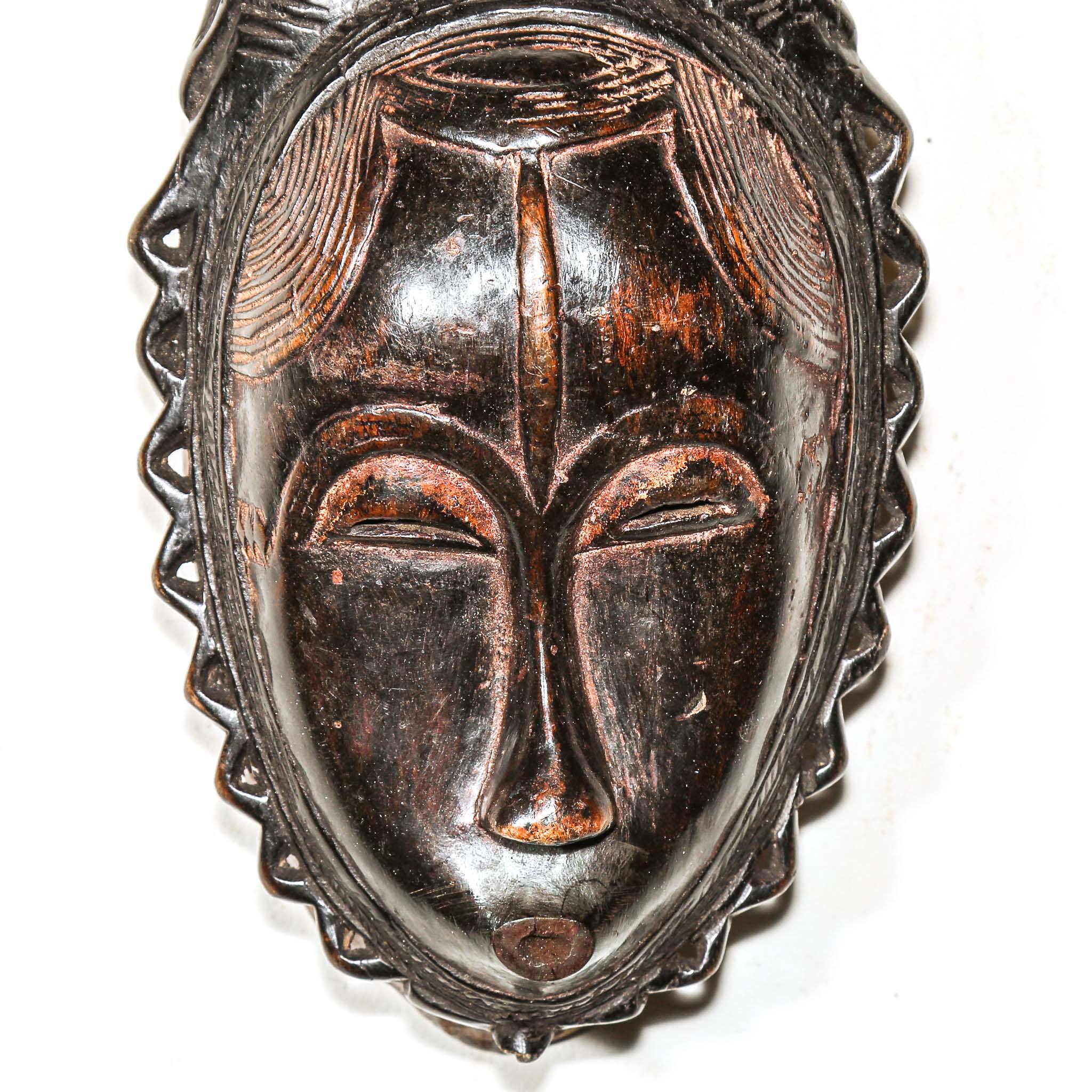 African mask with intricate designs on a white background