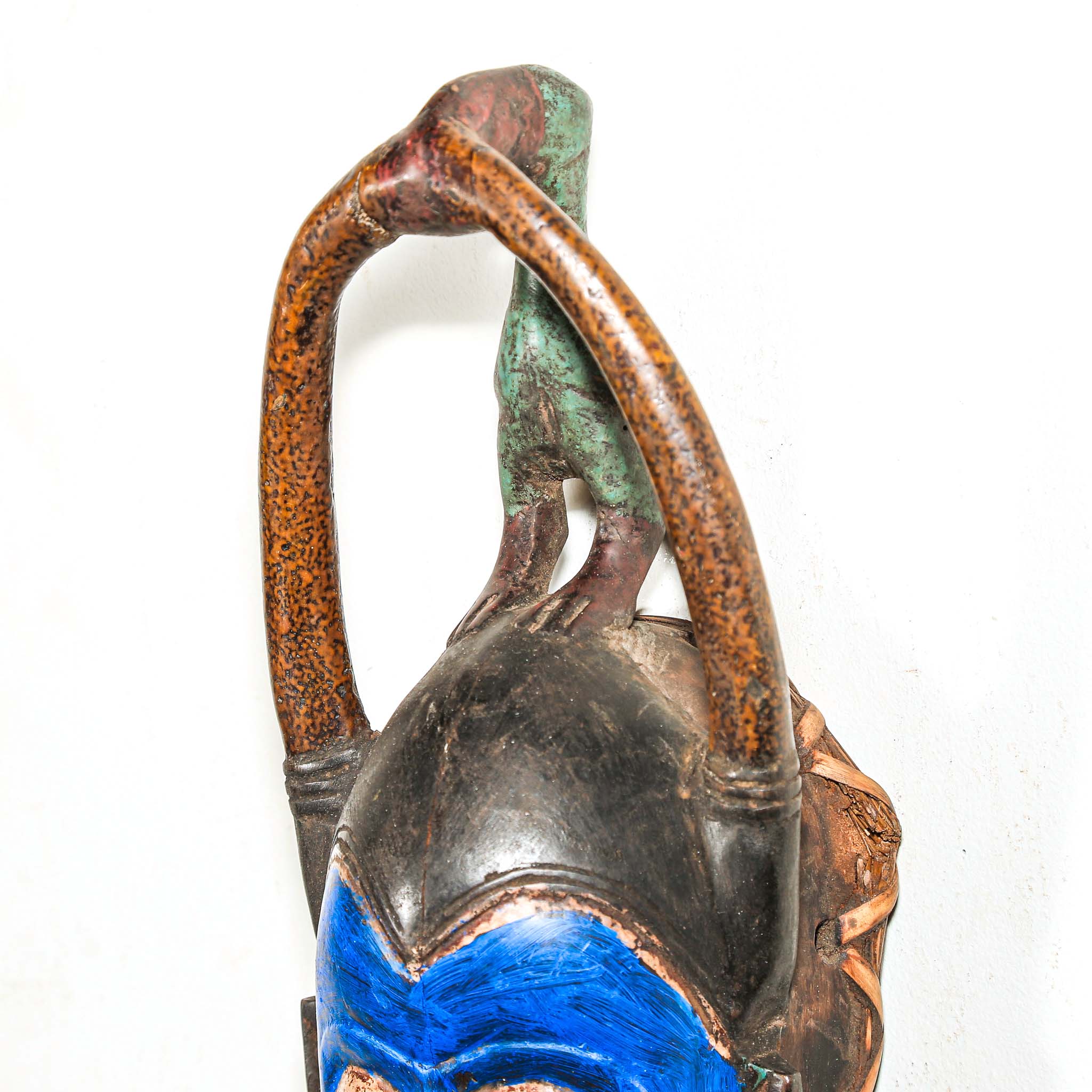 Decorative wooden African mask with blue face and brown arch on a white background authentic art and artist from Africa
