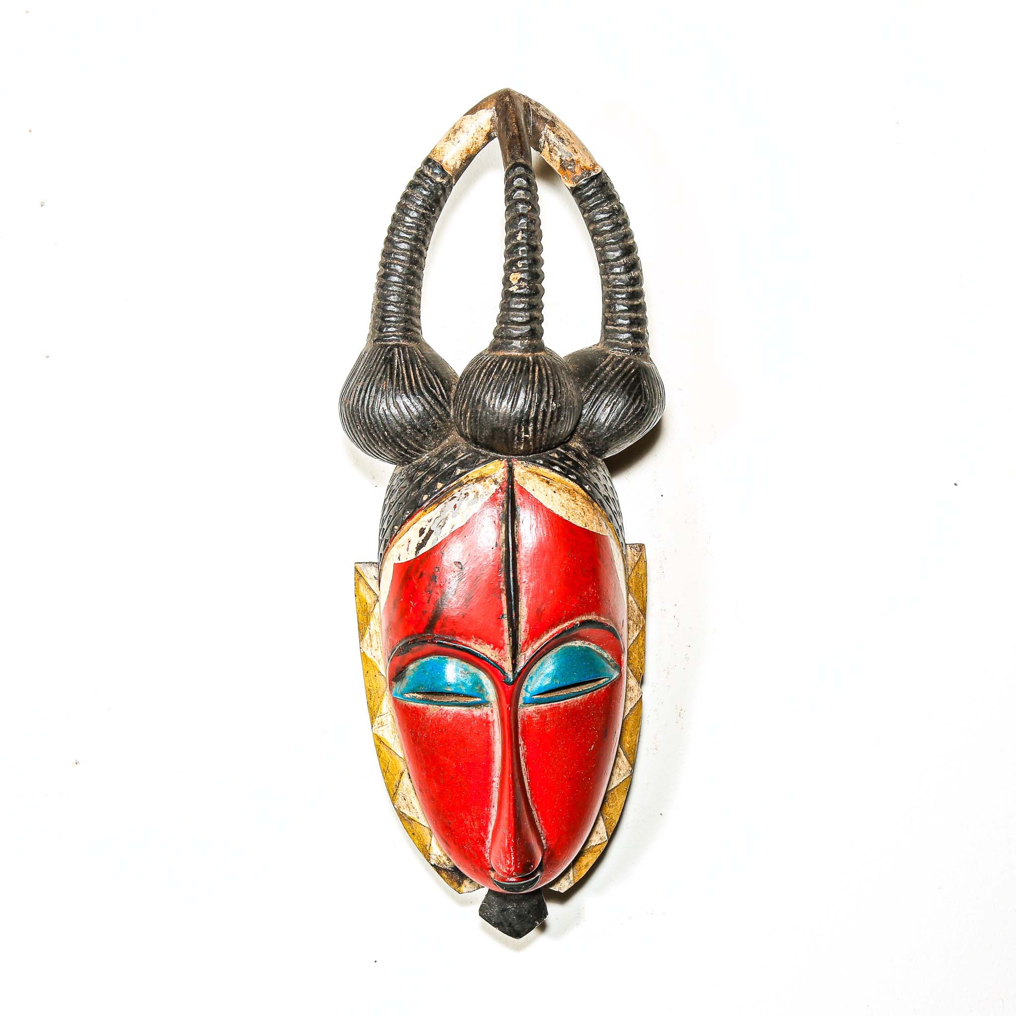 African decor mask with red face, blue eyes, and black hair on a white background