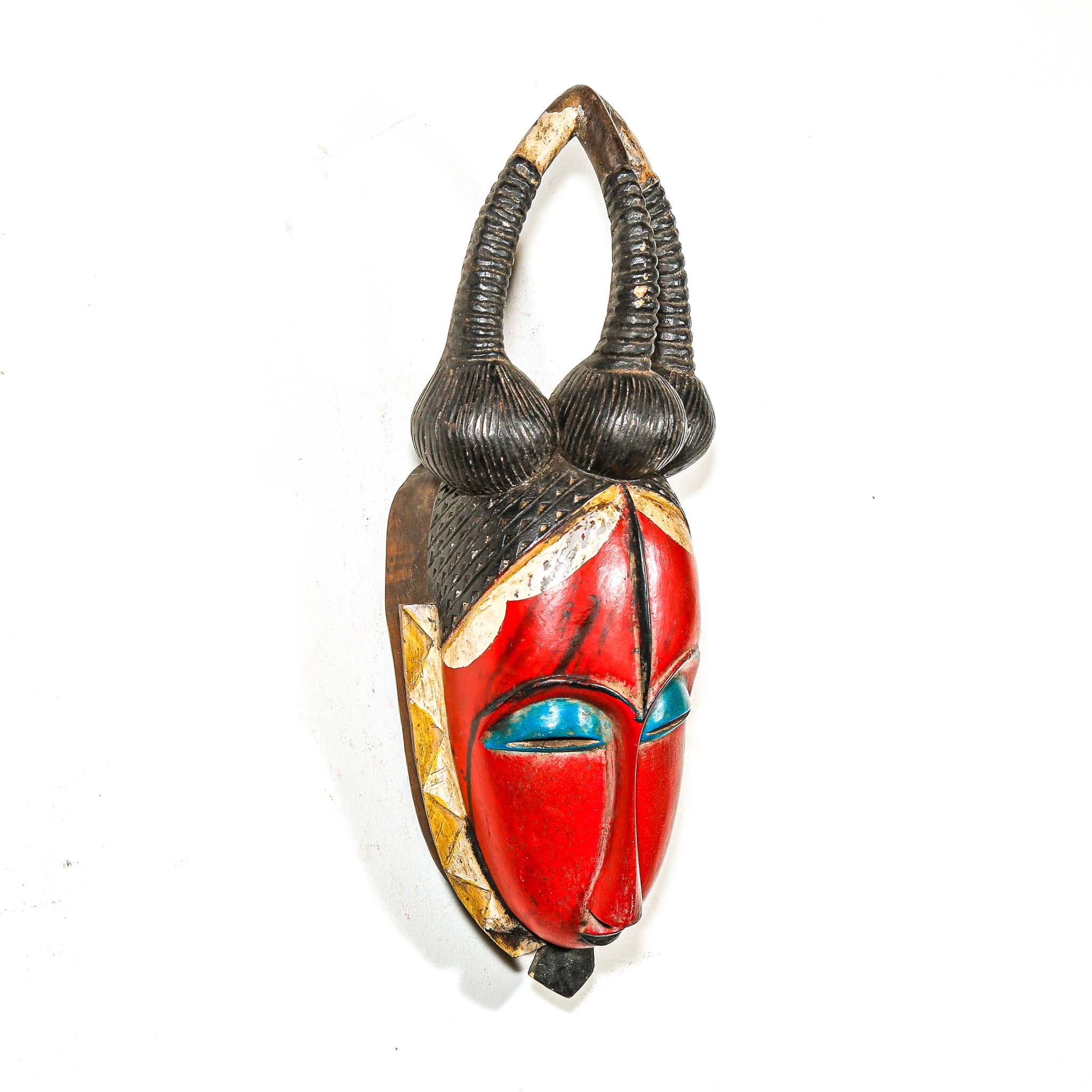 Colorful African mask with red face and black hair on a white background