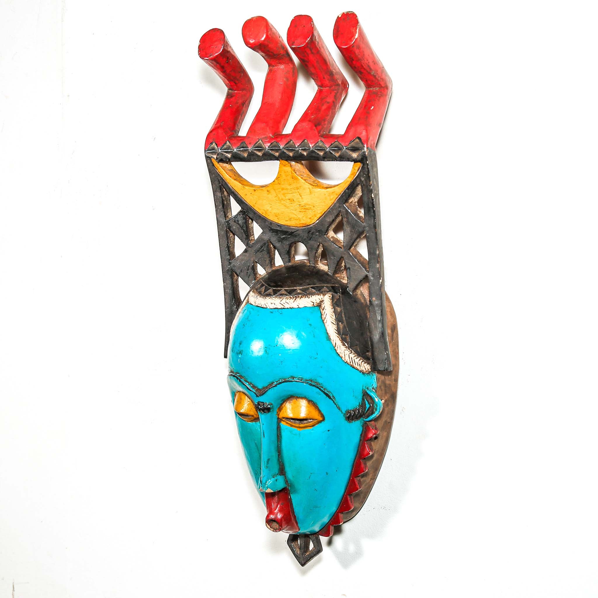 Colorful African wall mask with turquoise face, red and yellow accents on a white background
