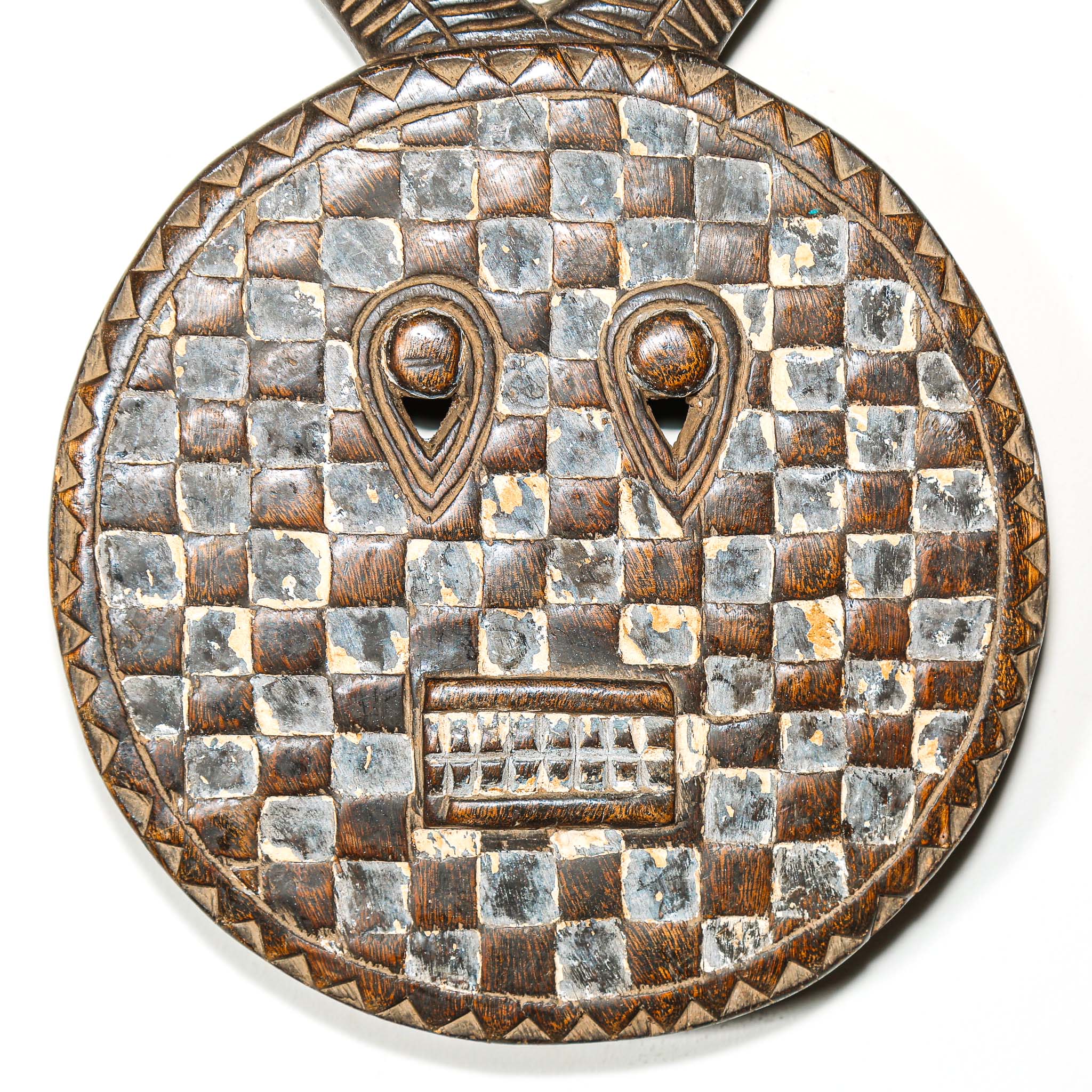 Decorative wooden traditional african mask with checkered pattern and eye design and horns on a white background