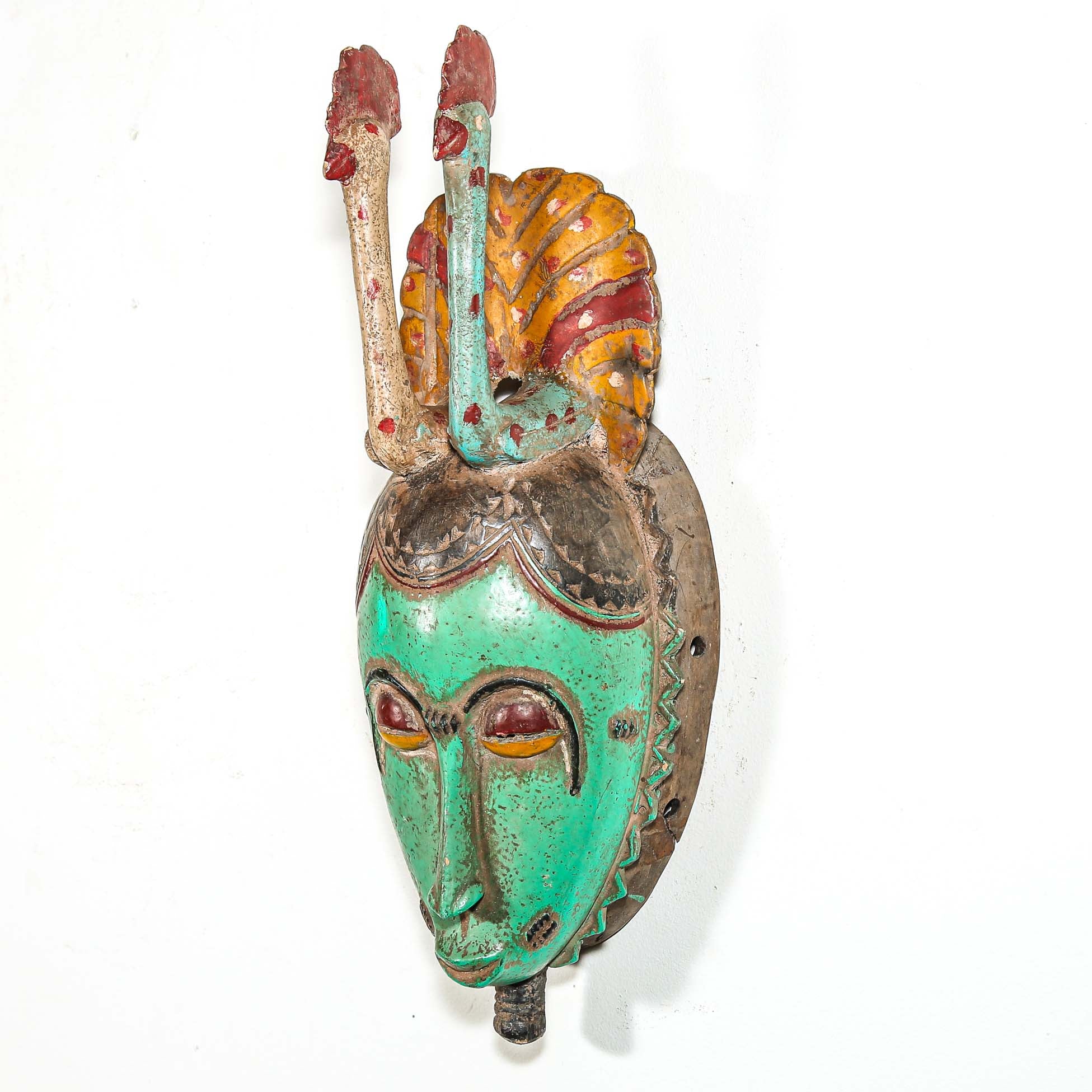 Tribal African mask with green face and colorful headdress with two birds on a white background