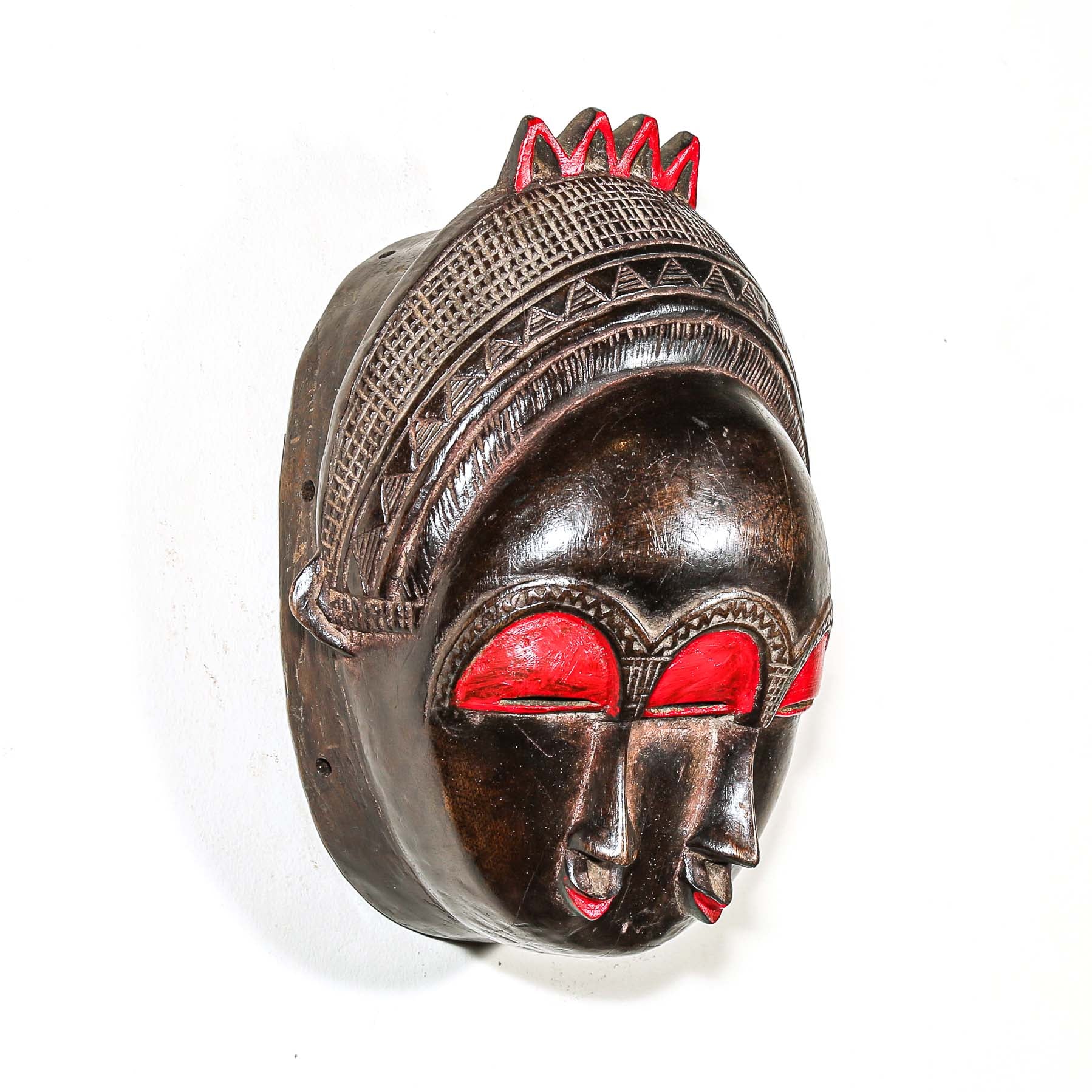 Decorative colorful african wooden mask with red accents on a white background