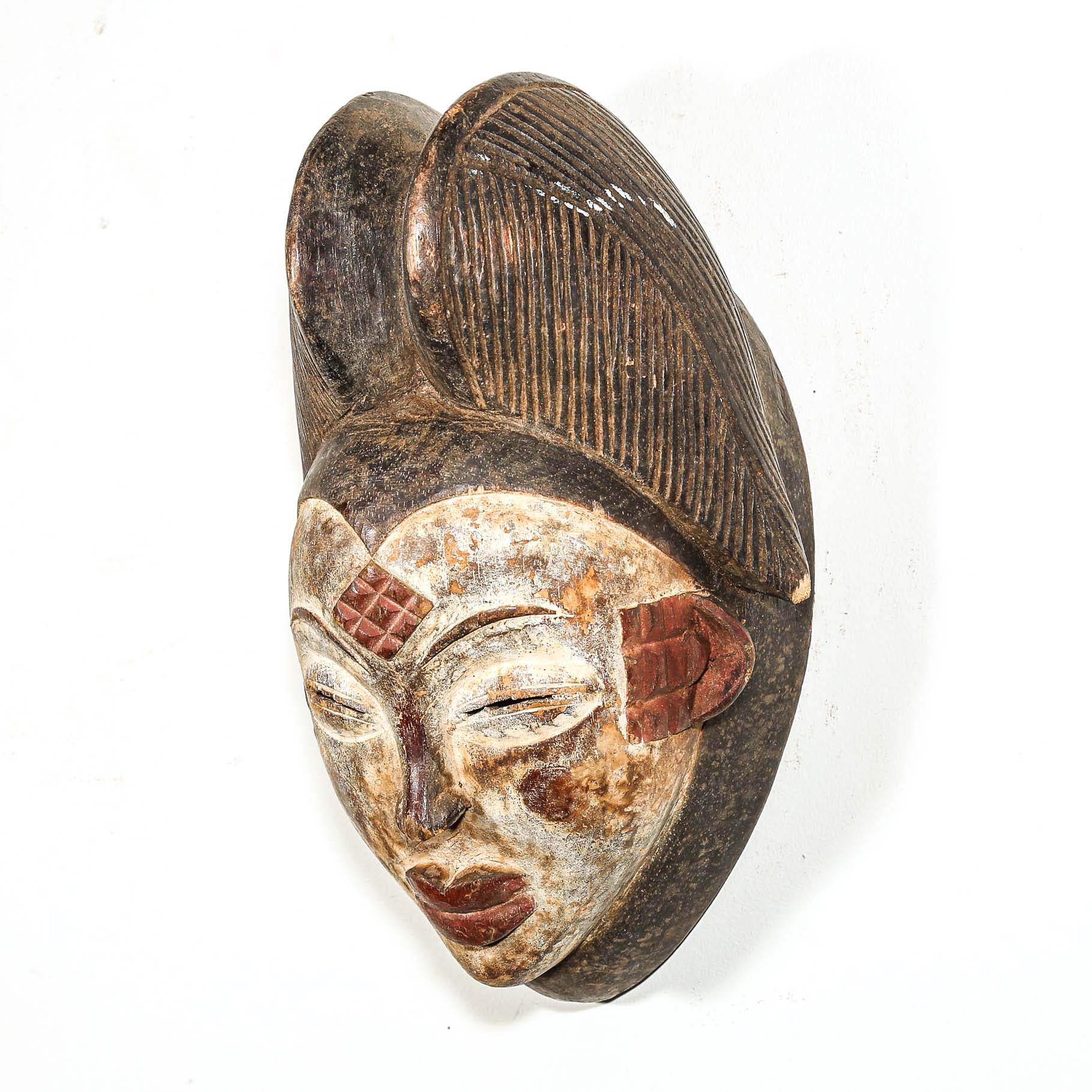 Wooden mask with detailed carvings on a white background