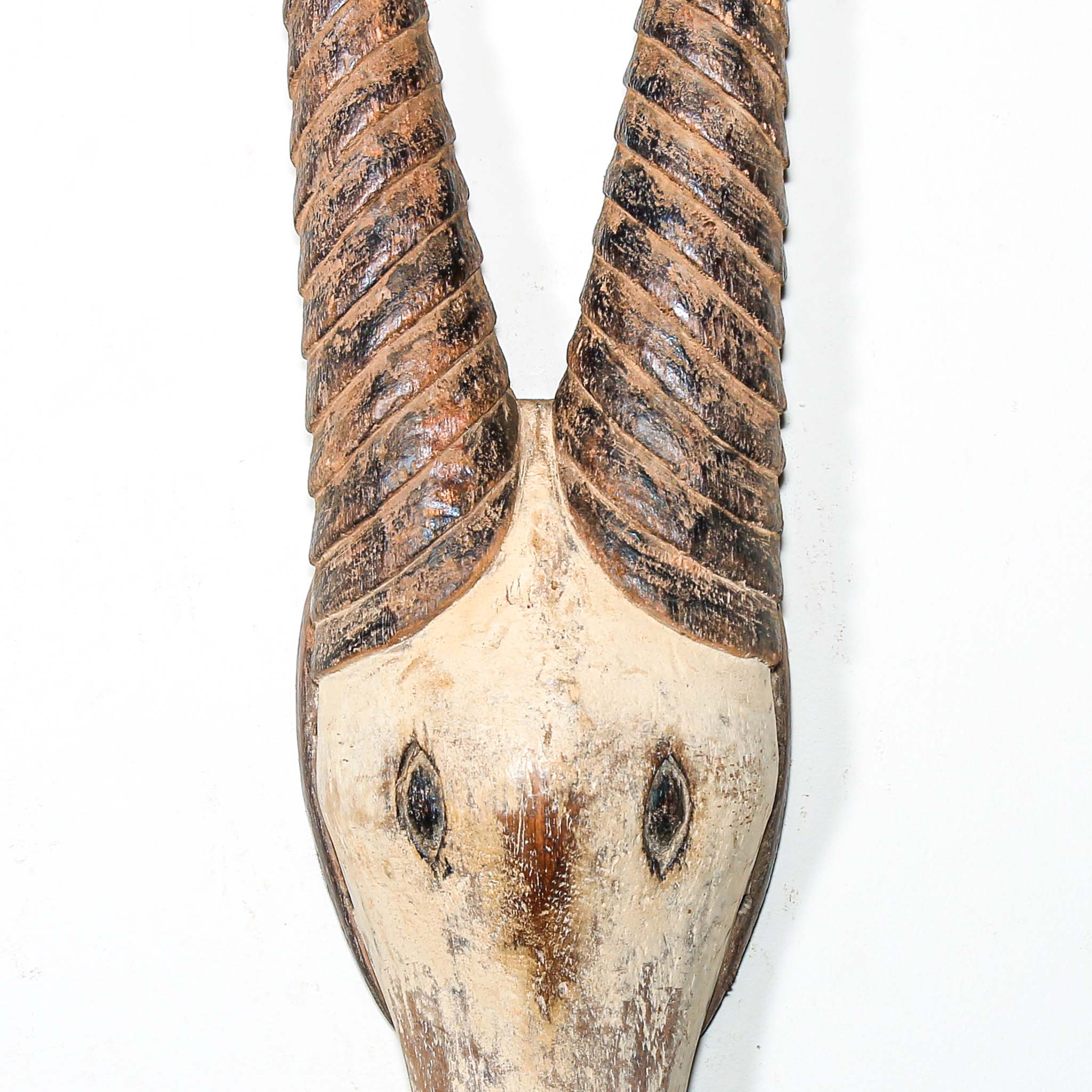 African mask in the shape of an antelope hanging on a white wall