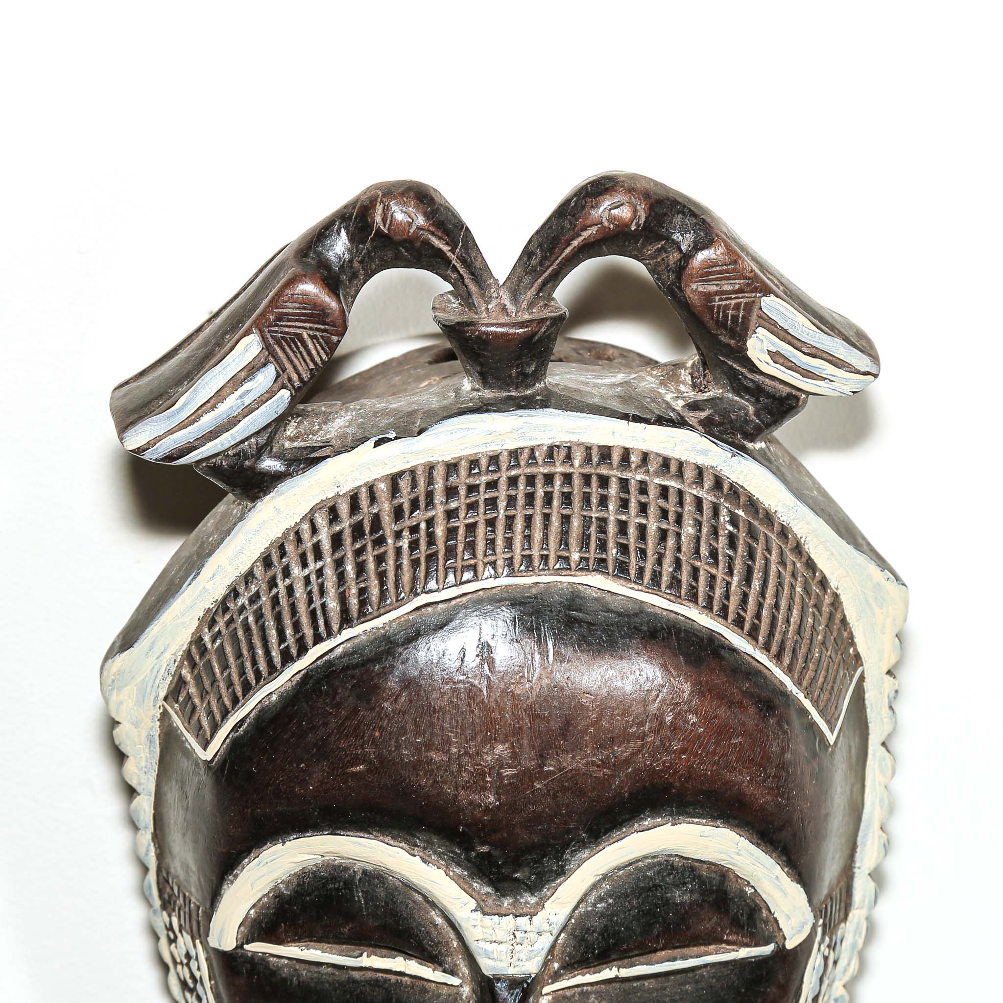 Decorative fine art african mask with white accents on a white background. Traditional art for sale