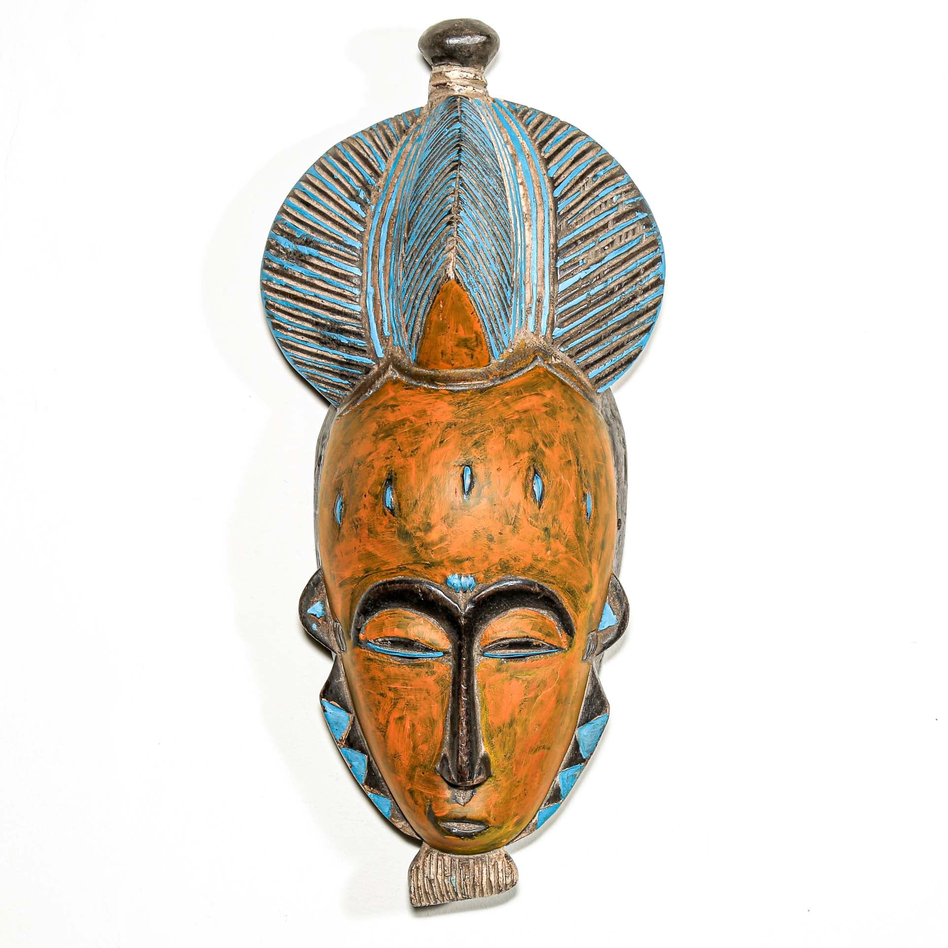 African art piece, specifically a yellow and blue wooden mask with geometric patterns on a white background. Tribal African art for sale.