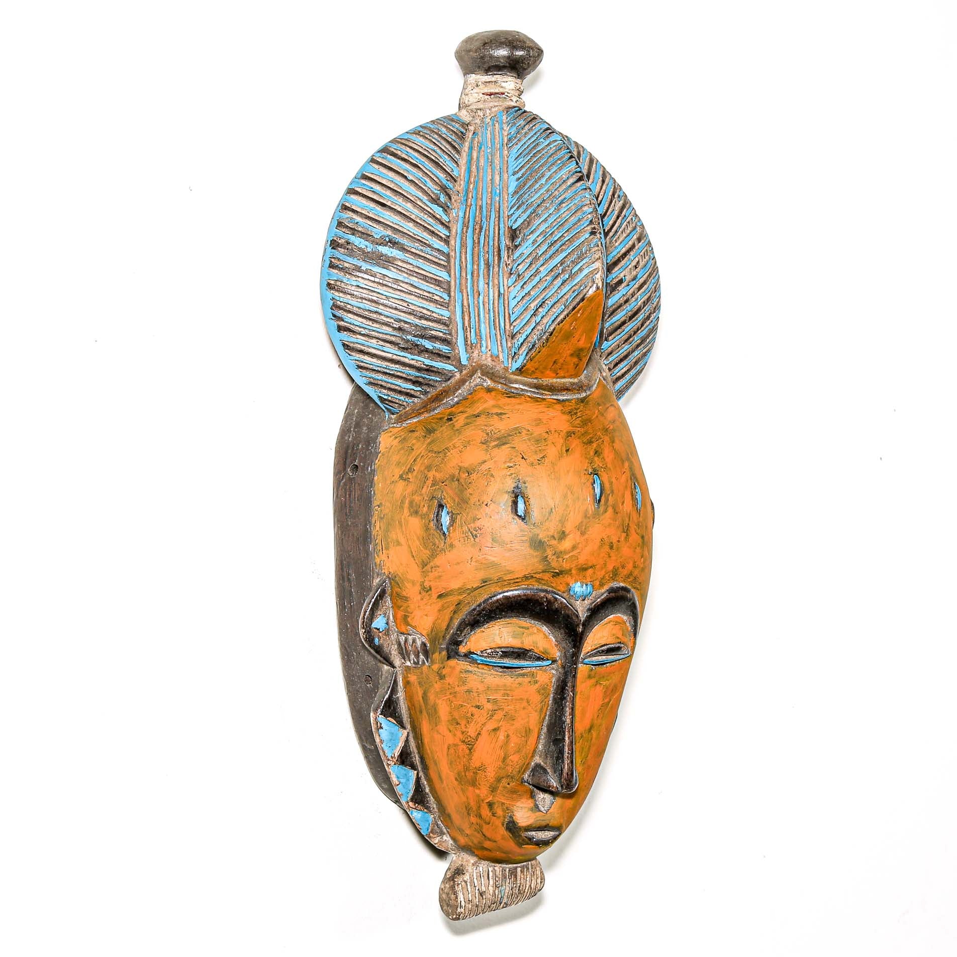 African art piece, specifically a yellow and blue wooden mask with geometric patterns on a white background. Tribal African art for sale.