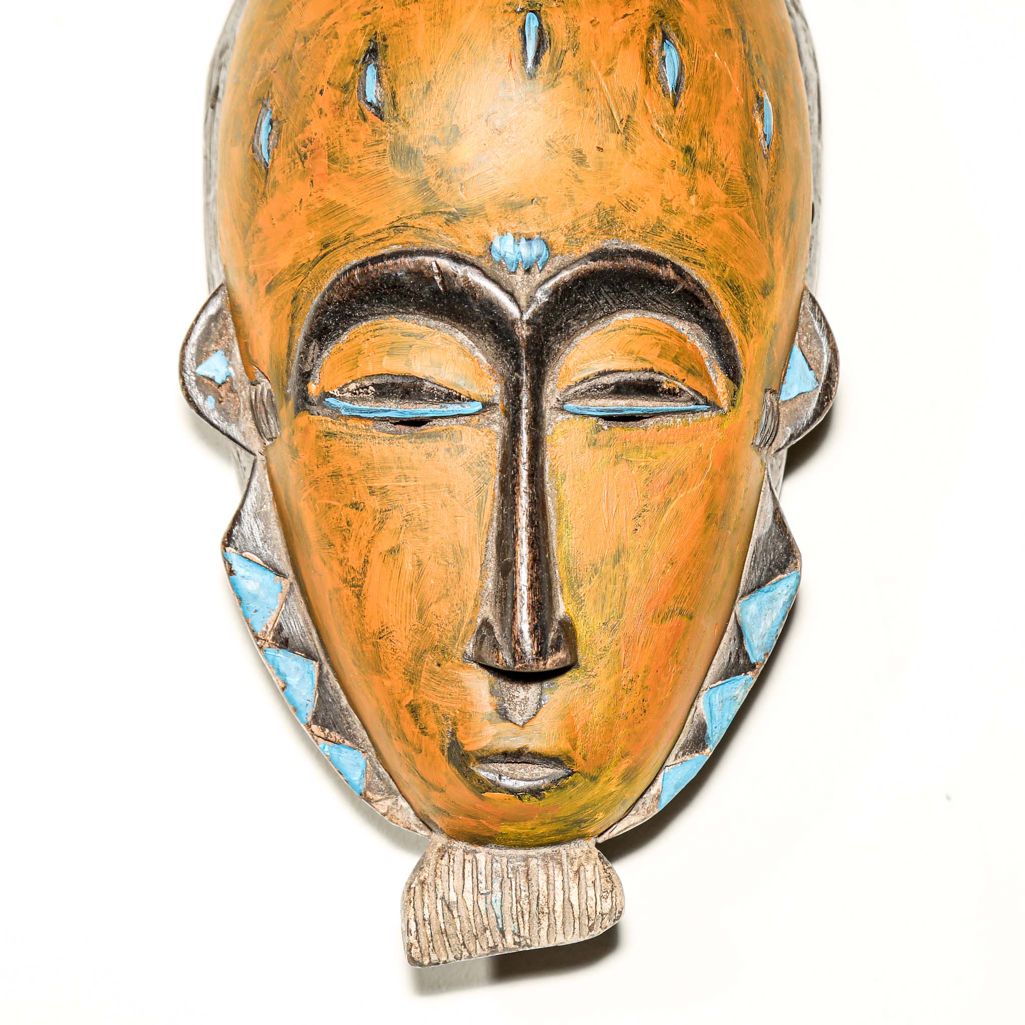 African art piece, specifically a yellow and blue wooden mask with geometric patterns on a white background. Tribal African art for sale.