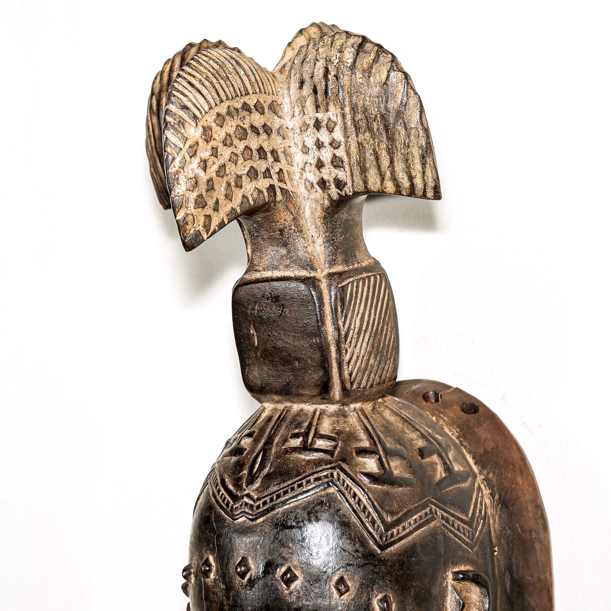 Fine African wood mask with intricate designs on a white background. Traditional tribal art for sale