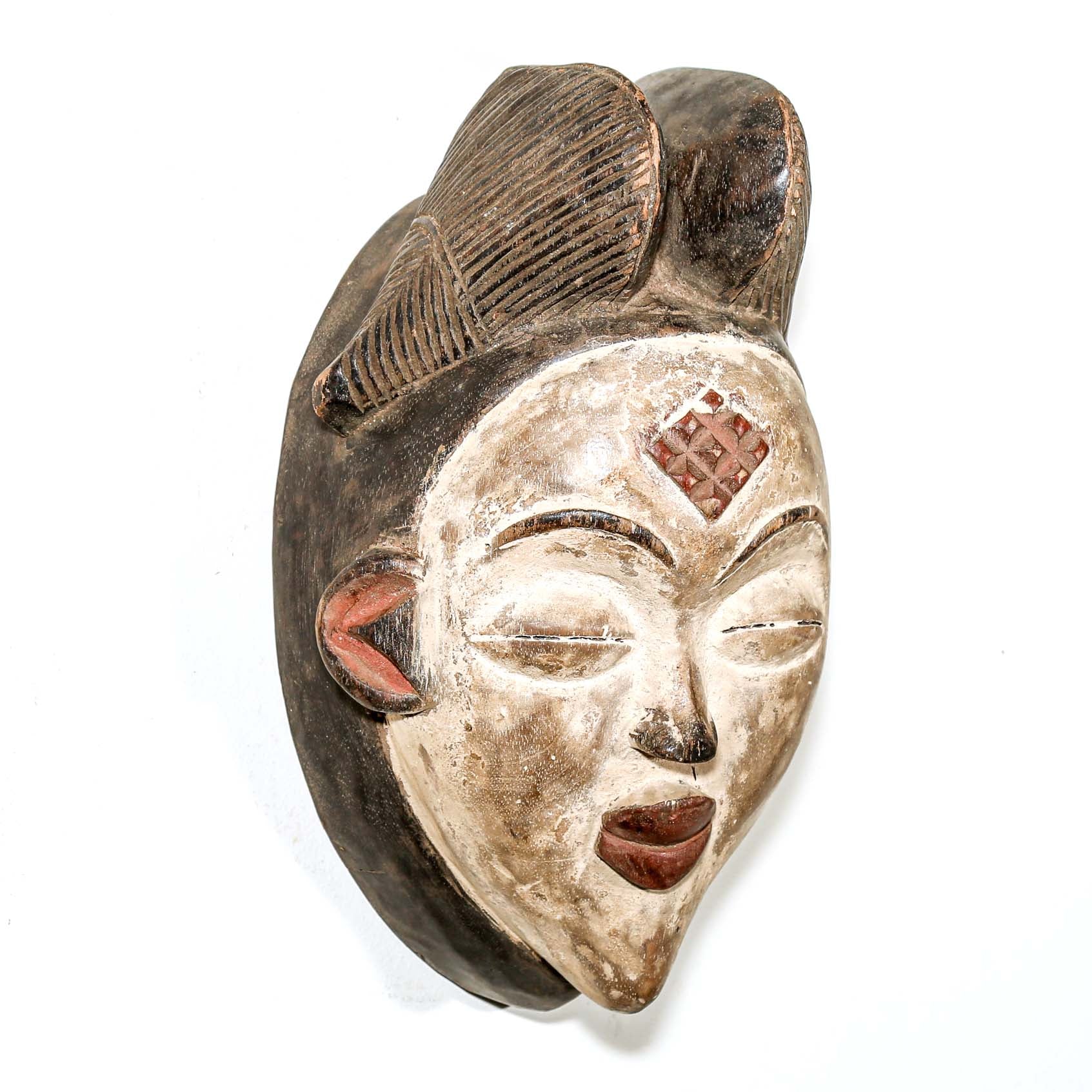 Carved wooden mask with detailed features on a white background