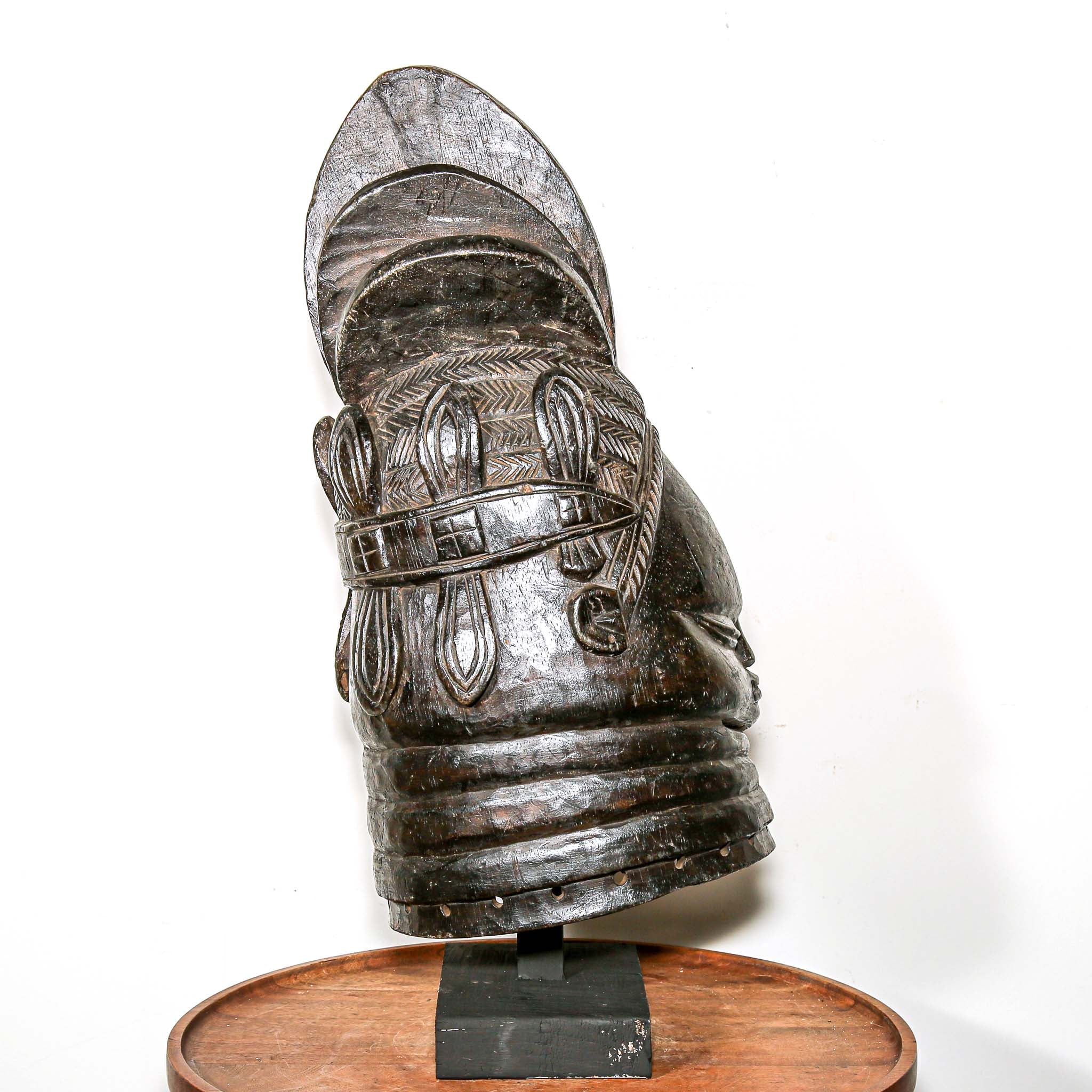 Decorative black african mask on a wooden home side table against a white background