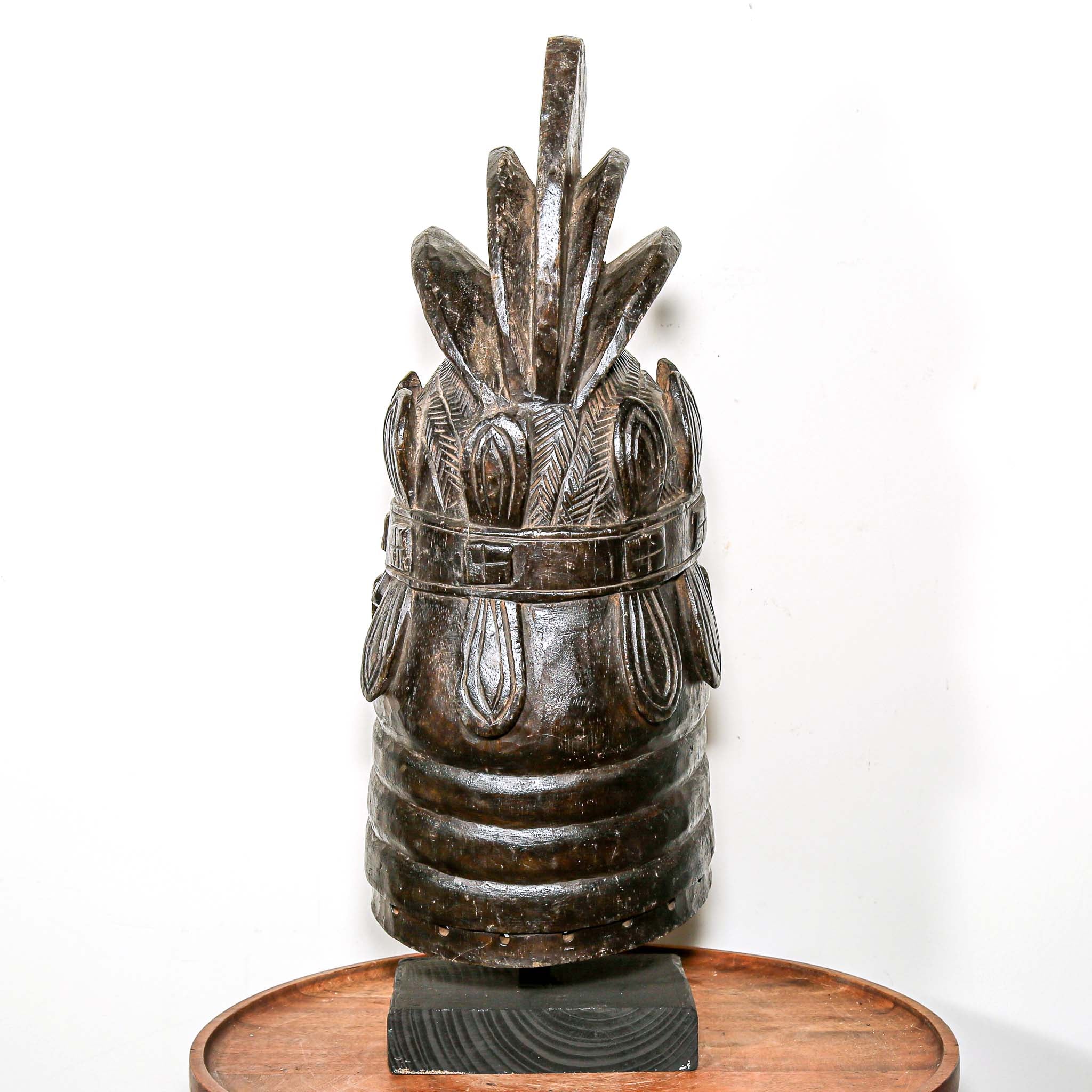 Decorative black african mask on a wooden home side table against a white background