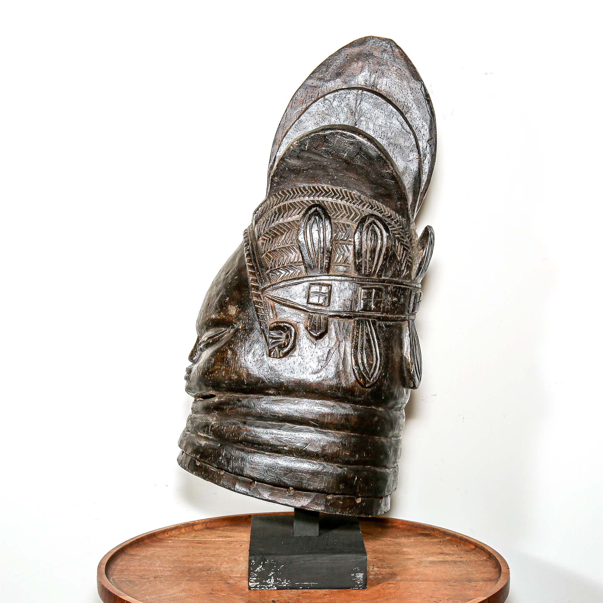Decorative black african mask on a wooden home side table against a white background