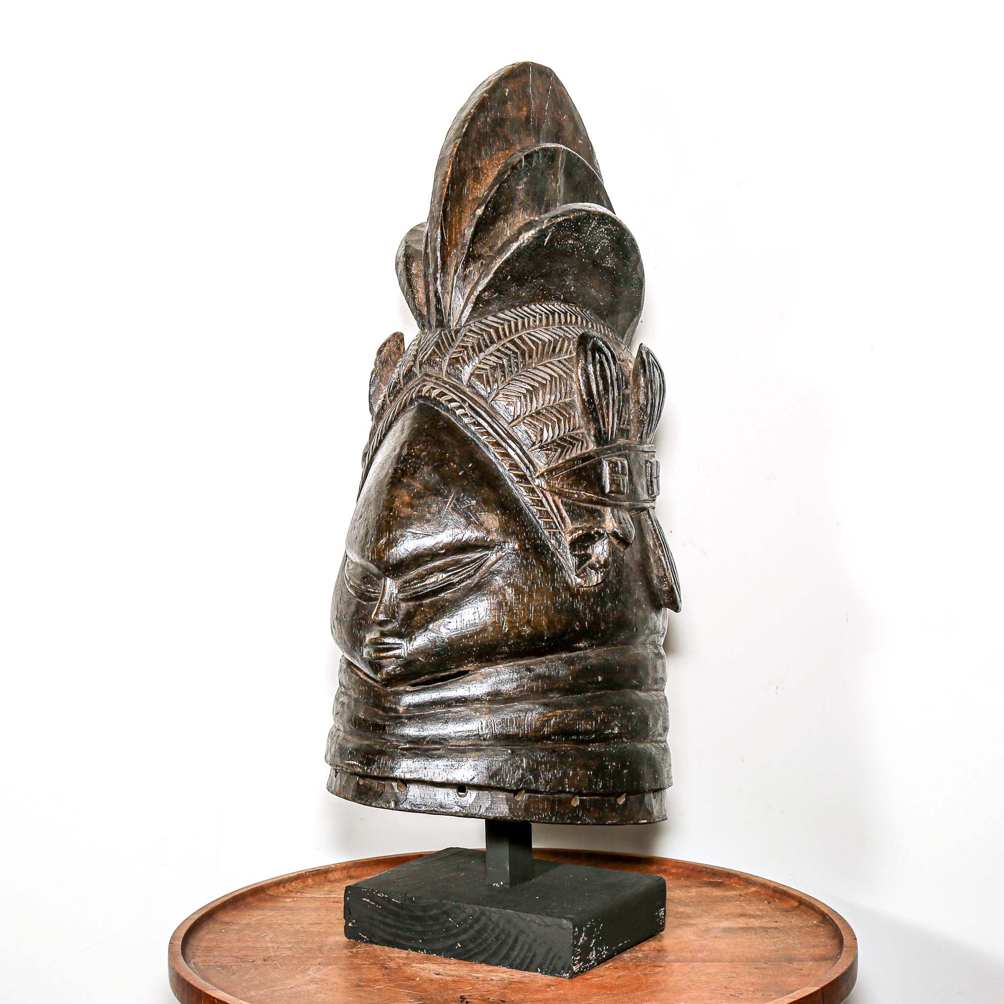 Decorative black african mask on a wooden home side table against a white background