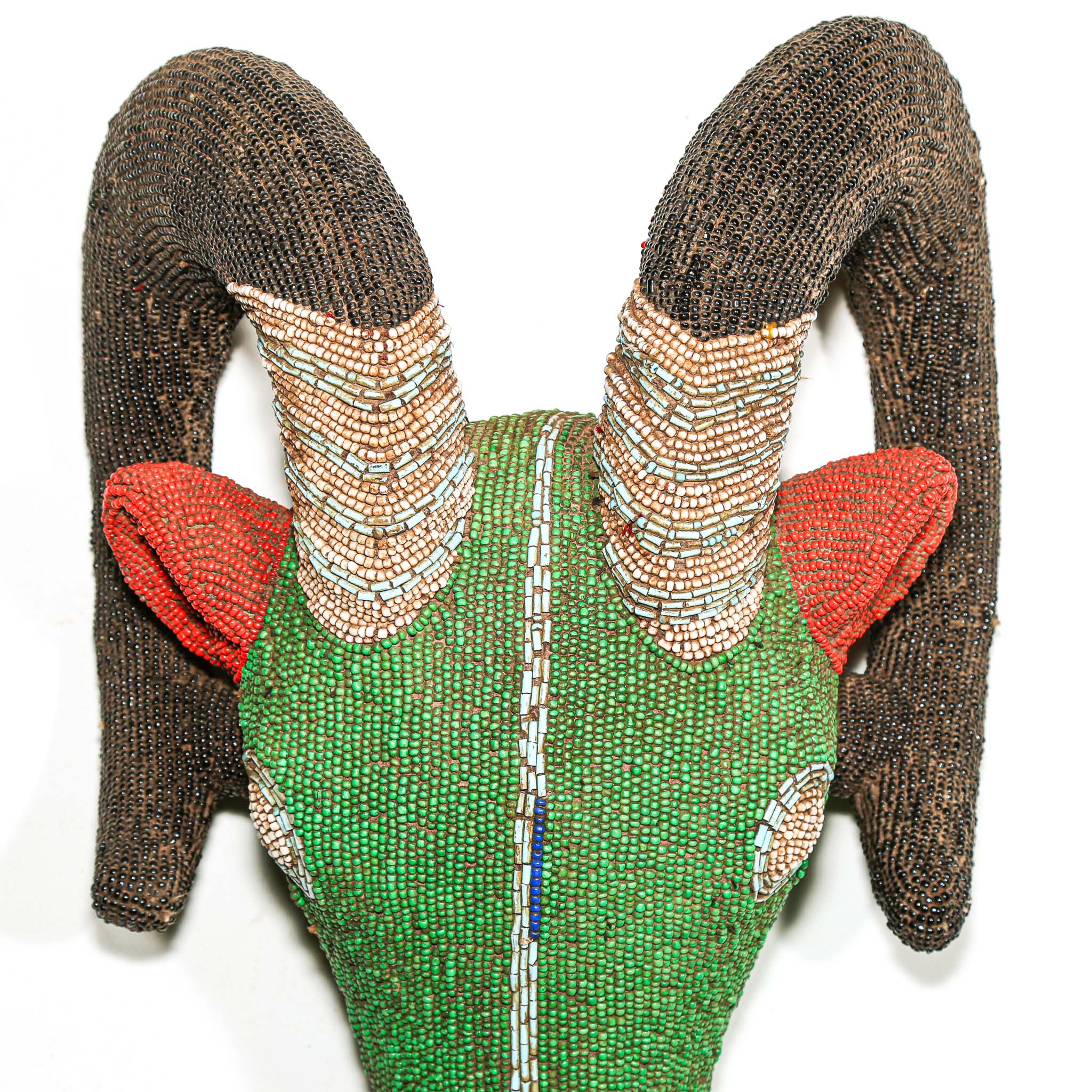 Beaded ram sculpture with green body, red ears, and brown horns on a white background