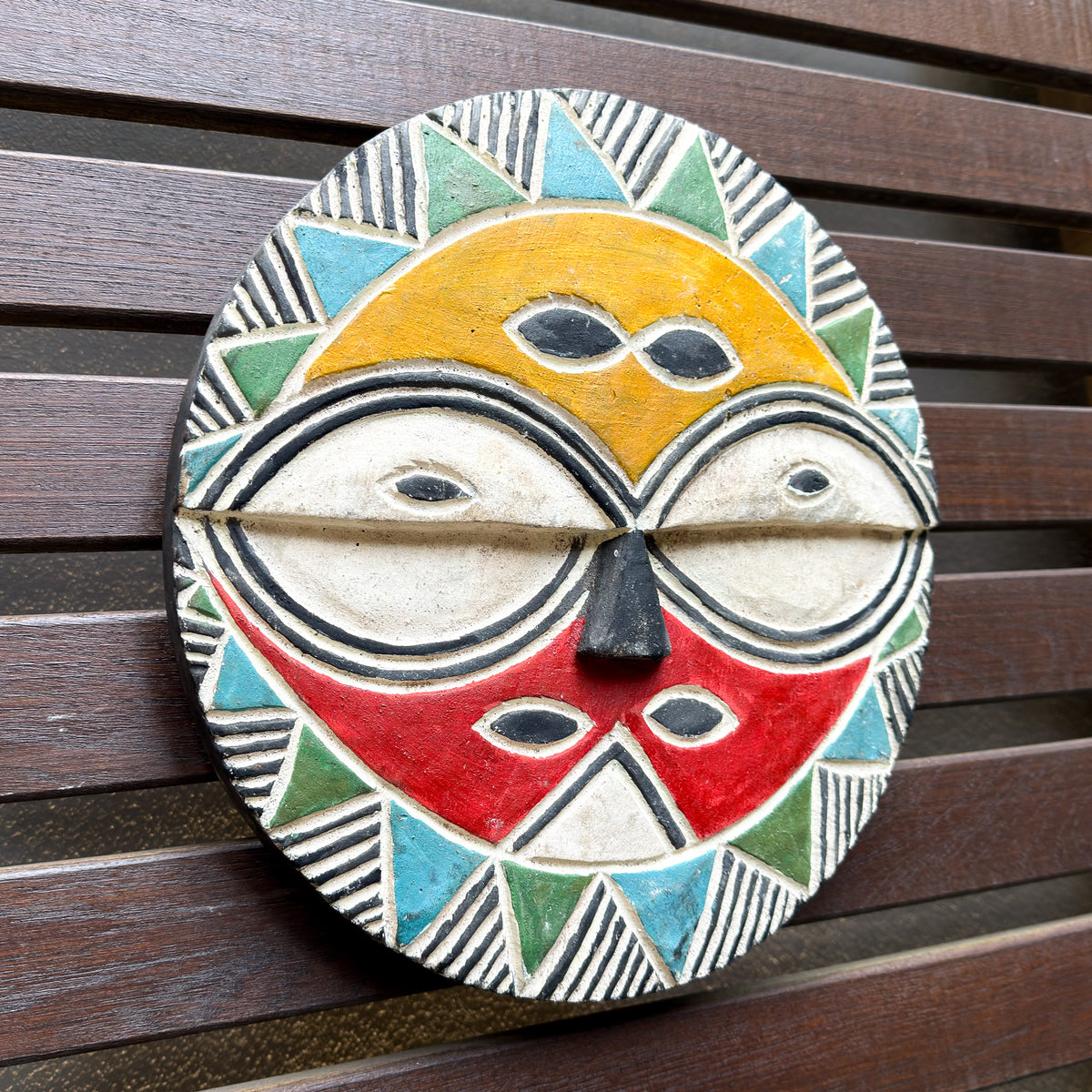 Colorful Teke African mask featuring bright painted designs, carved facial features, and a striking decorative form