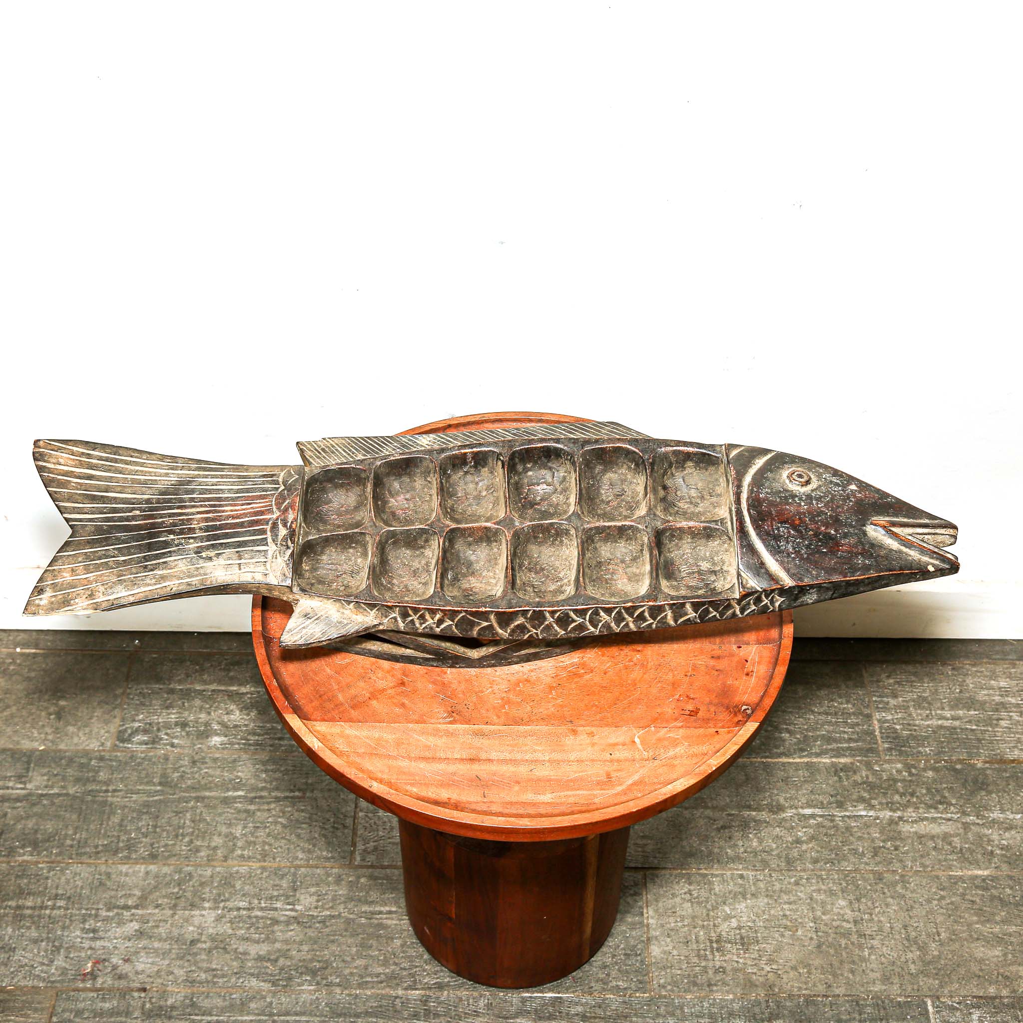 Wooden fish-shaped platter on a wooden stand with a white background