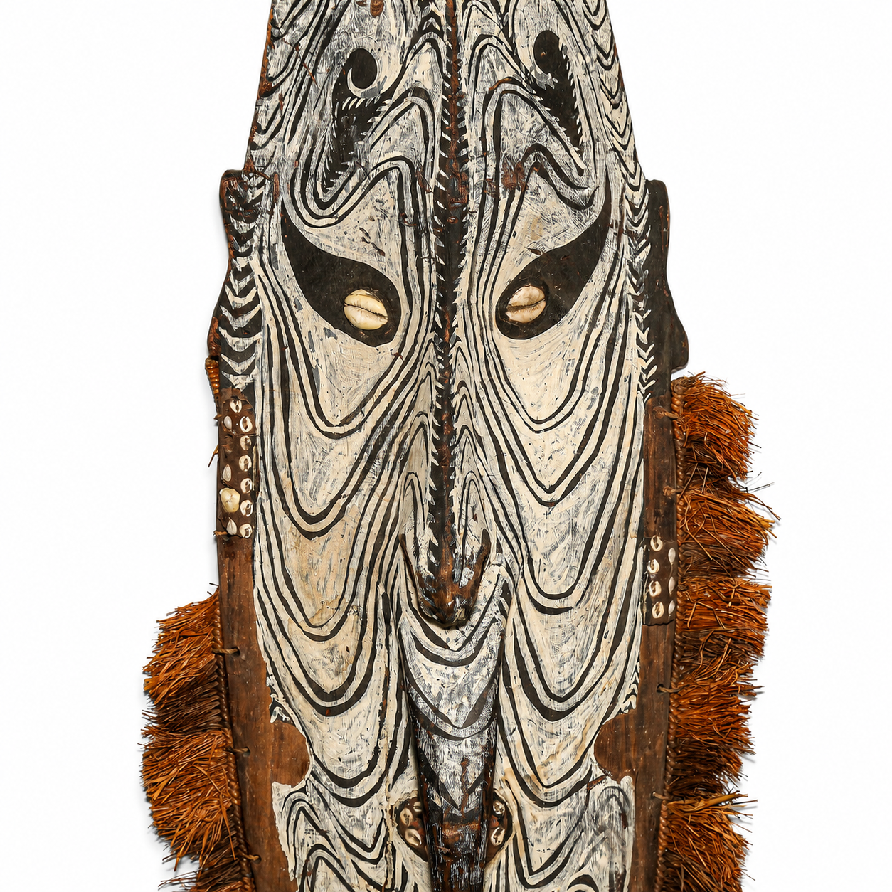 Decorative wooden mask with intricate patterns and fringes on a white background