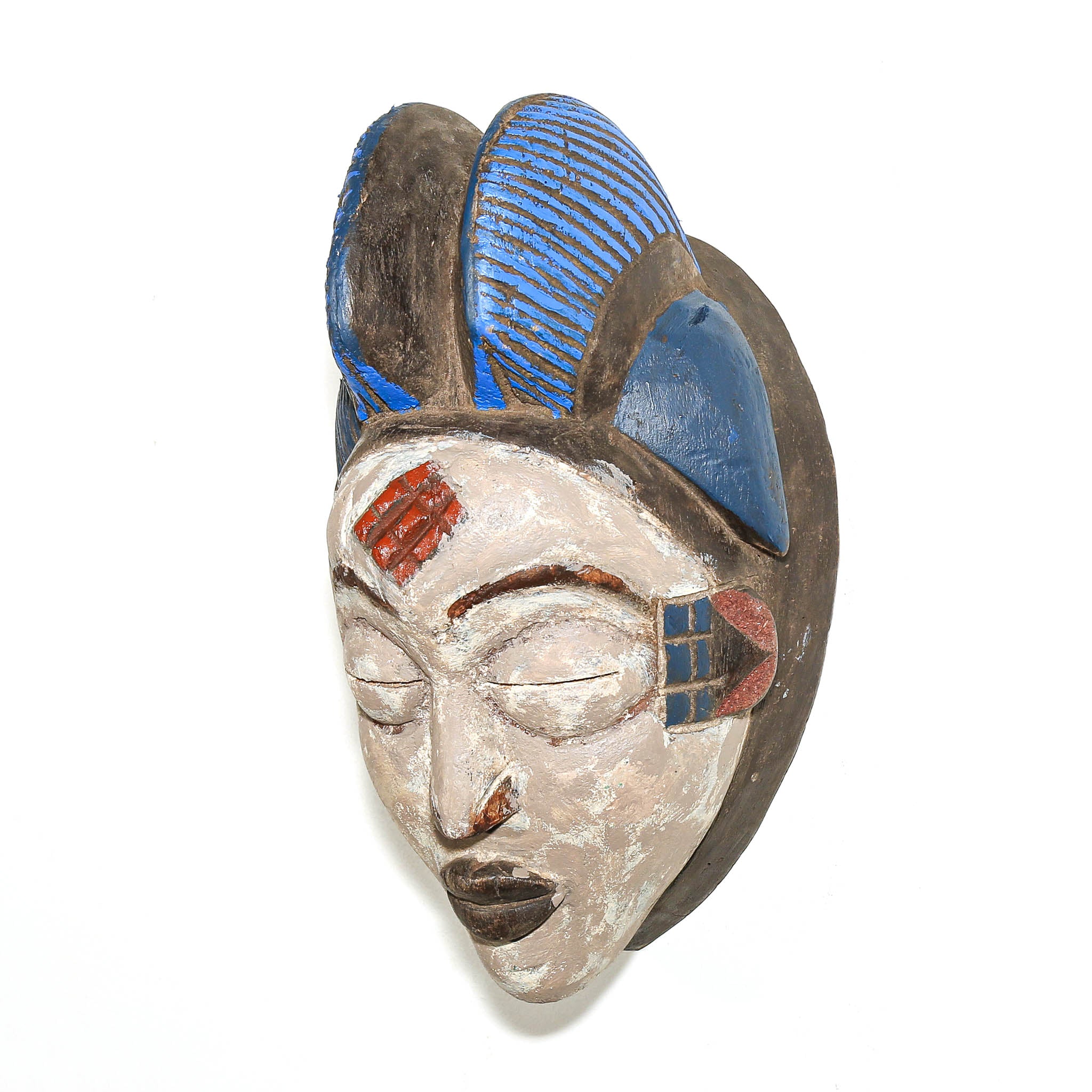A hand-carved African wooden mask with a stylized face, featuring blue and red painted details on a white background.