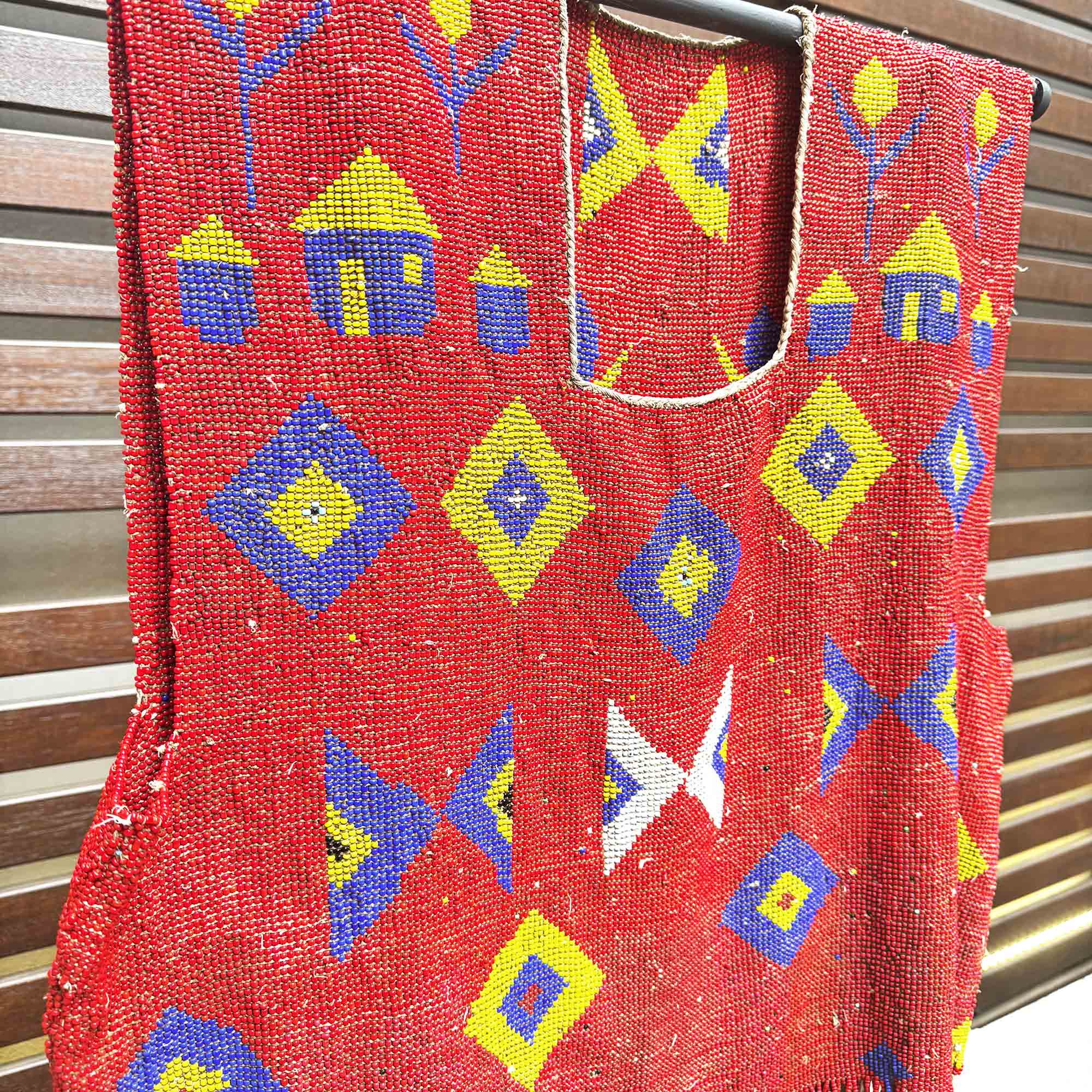 Red african fashion with colorful geometric patterns hanging against a wooden background