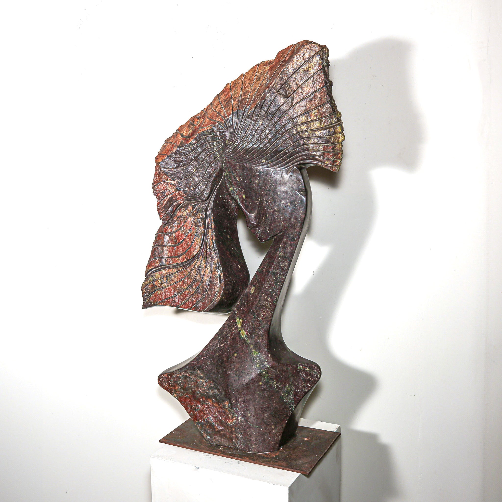 Purple Stone Sculpture of a Woman Titled "Windswept" by Lovemore Bonjisi shown in a home with a white wall