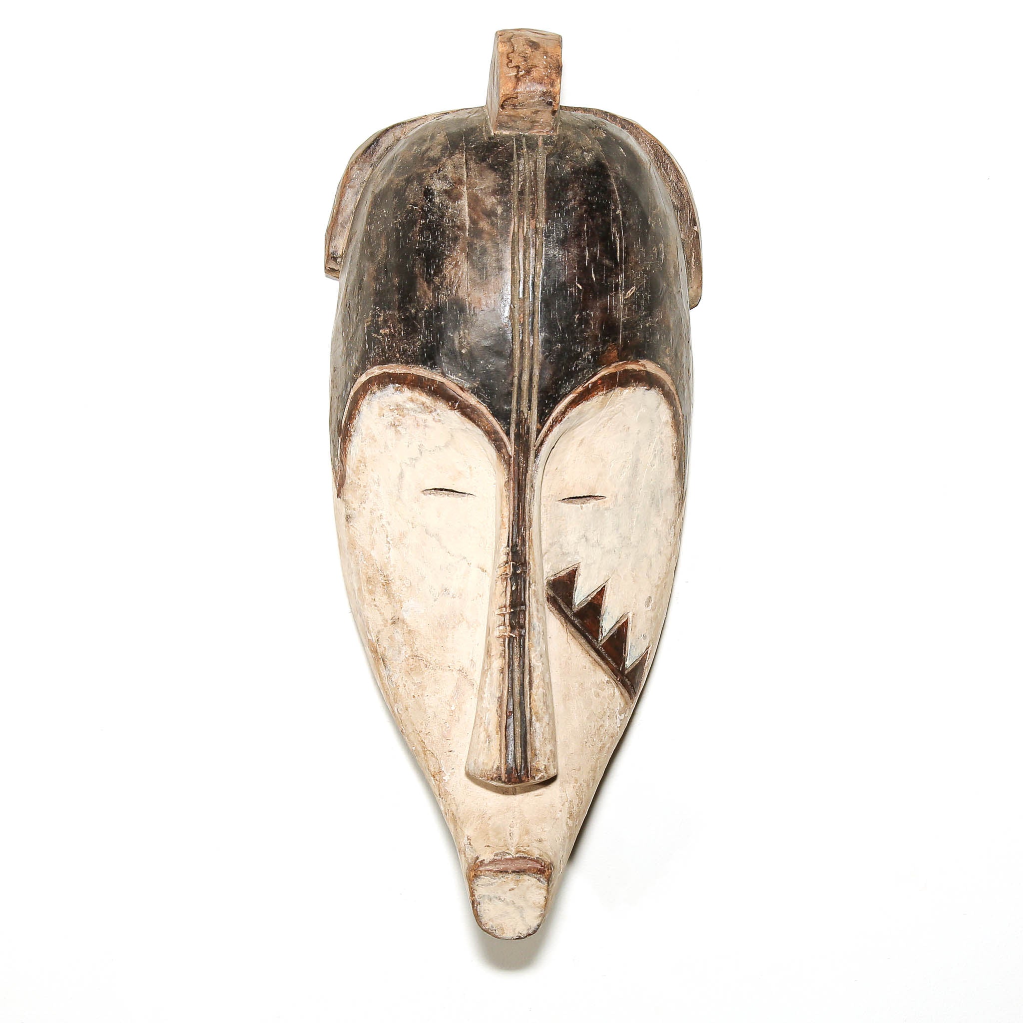 A hand-carved African wooden mask with a stylized face, featuring a dark brown top section and a lighter beige lower section with carved facial details, shown against a plain white background.