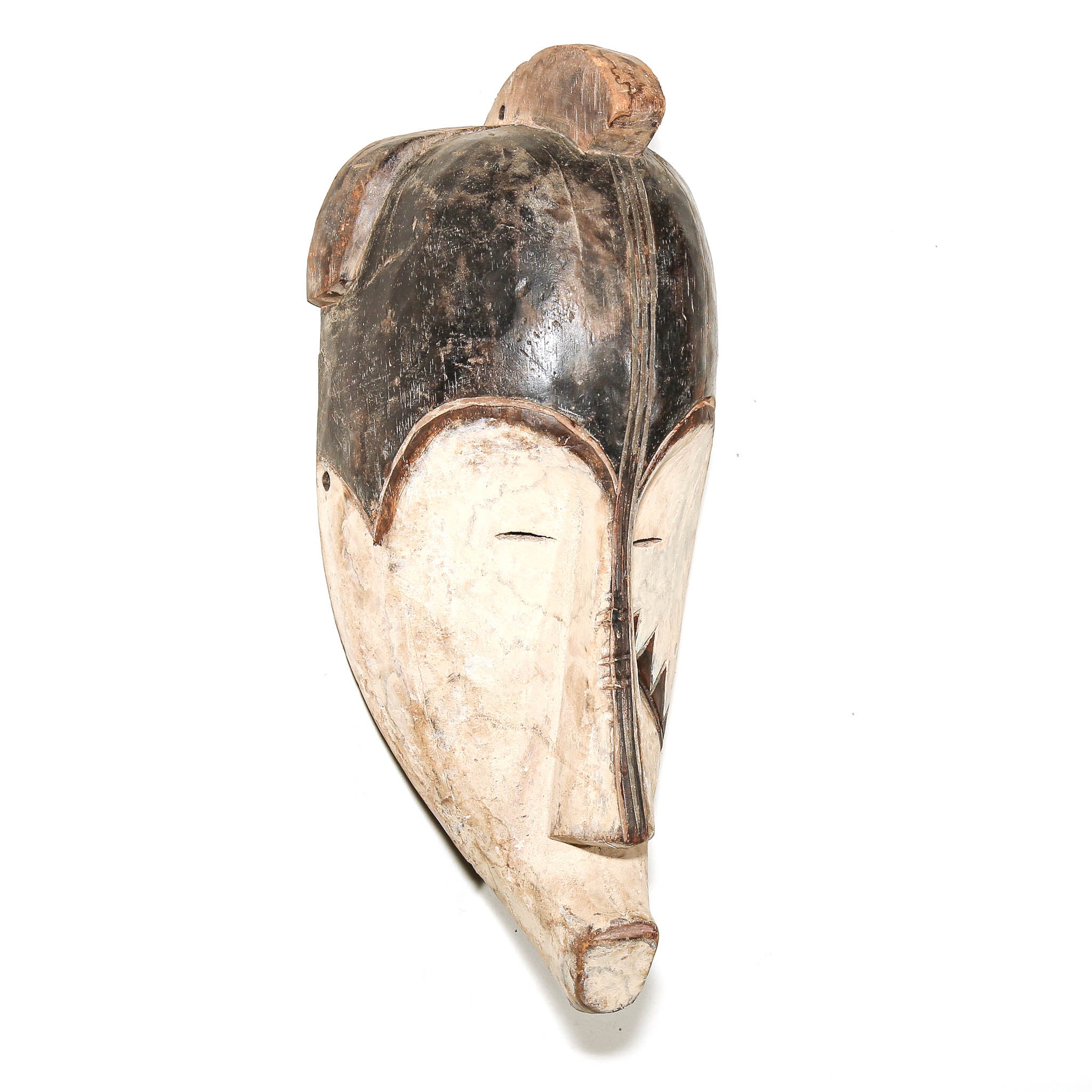 A carved wooden mask with a stylized face, featuring a dark brown top section and a lighter beige lower section, photographed against a plain white background.
