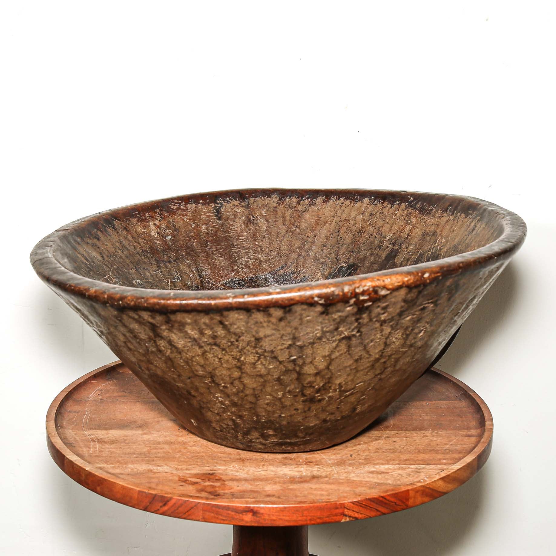 Vintage wooden bowl on a wooden stand against a white background