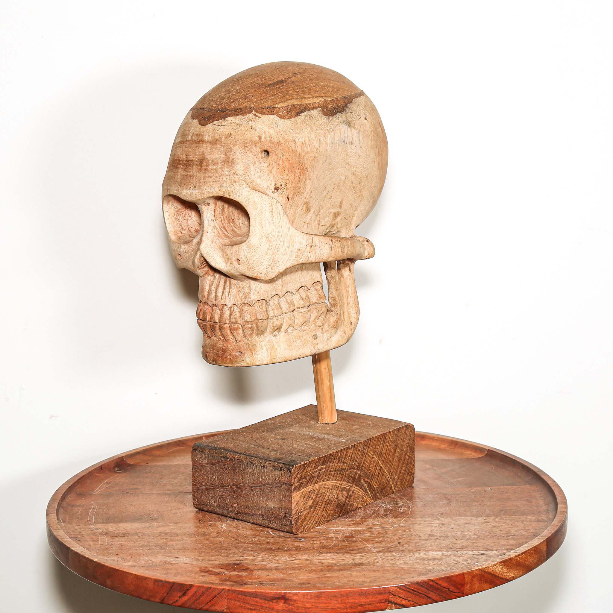 Hand Carved African Wooden human skull sculpture on a wooden base in a living room on a side table