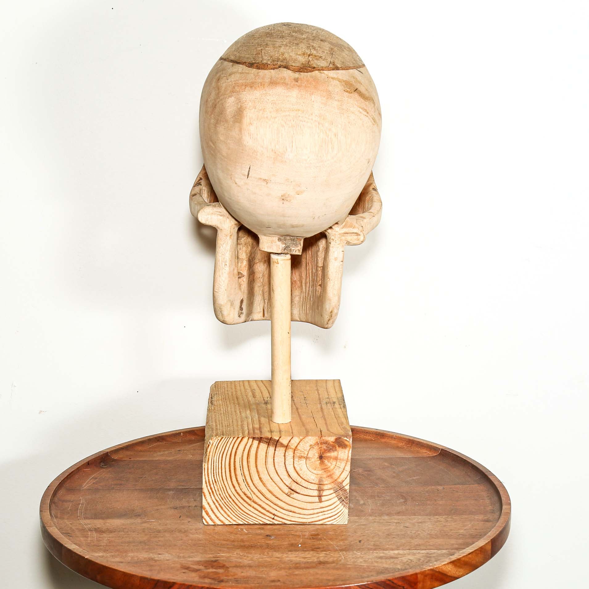 Wooden sculpture of a head and shoulders on a wooden base against a white background
