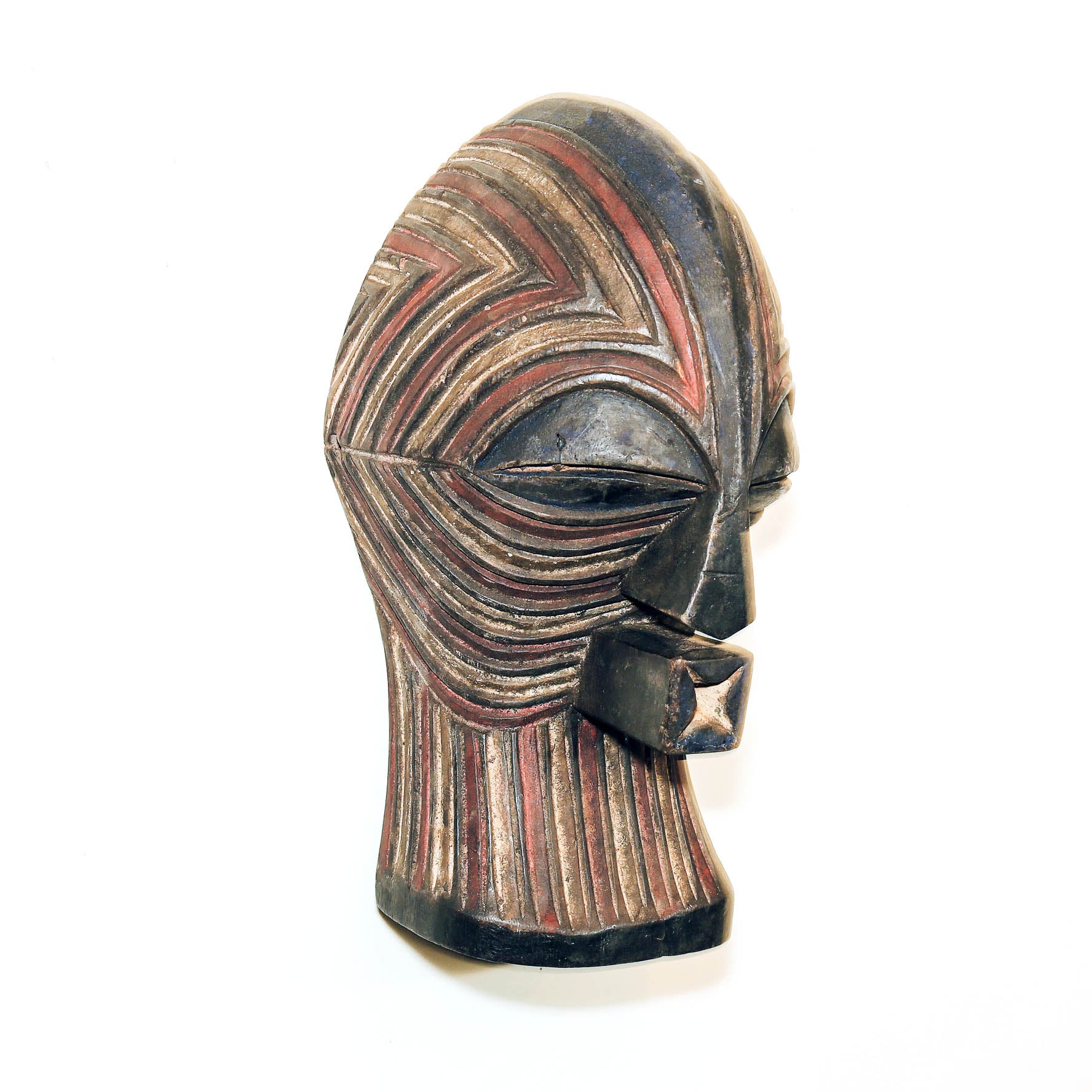 A carved wooden African-style mask head sculpture with geometric patterns in black, brown, and red, shown against a plain white background.